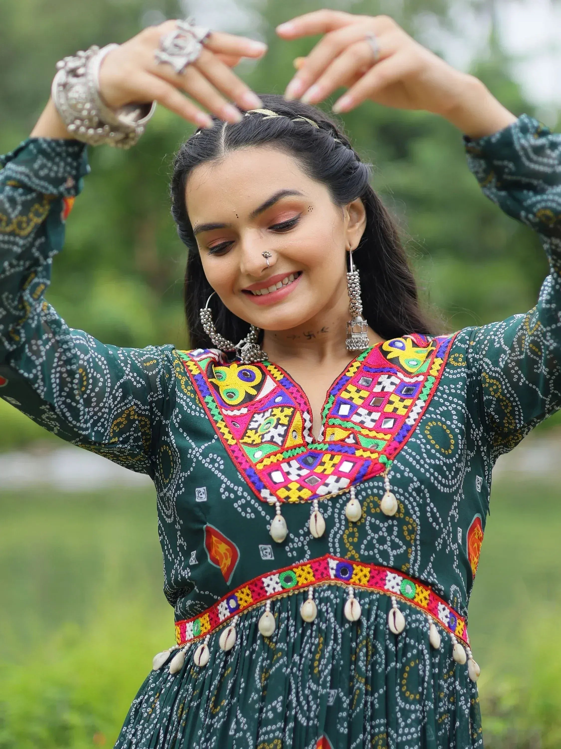 Woman in vibrant green ethnic dress with colorful embroidery and shell accents, styled for traditional occasions.