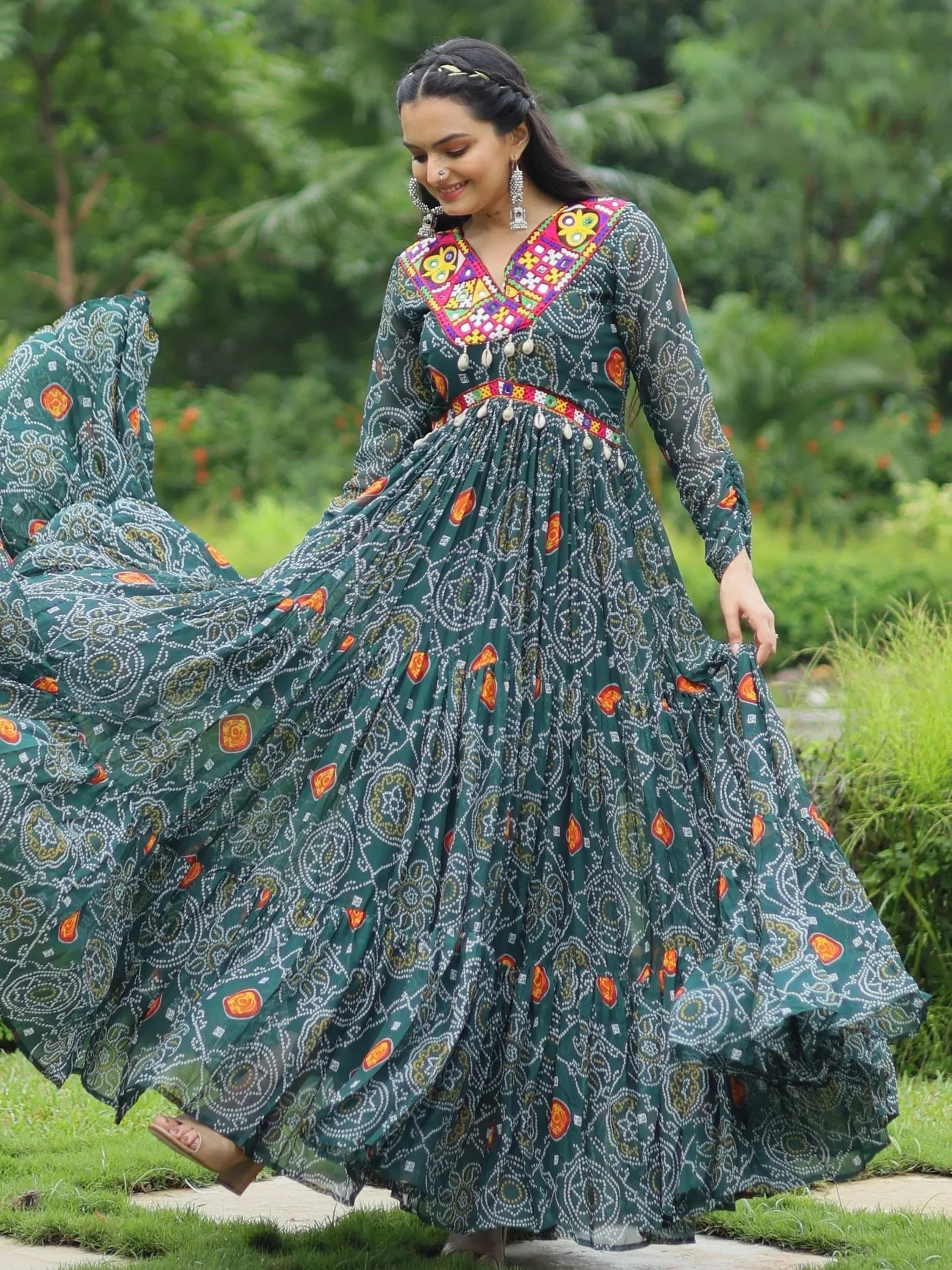 Woman twirling in green printed ethnic gown with colorful embroidery, perfect for Indian festive occasions.