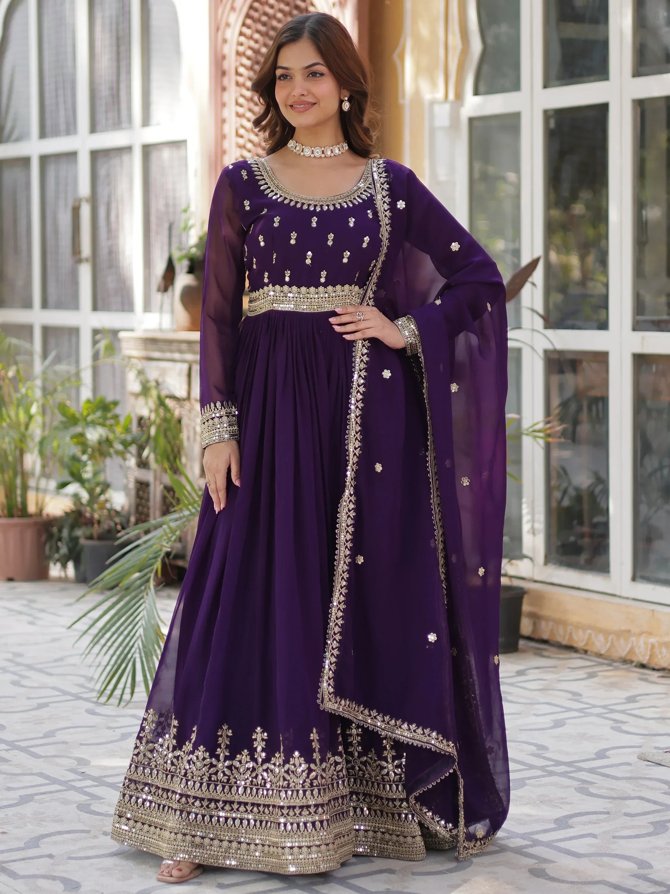 Woman wearing purple embroidered Indian ethnic gown with gold accents outdoors