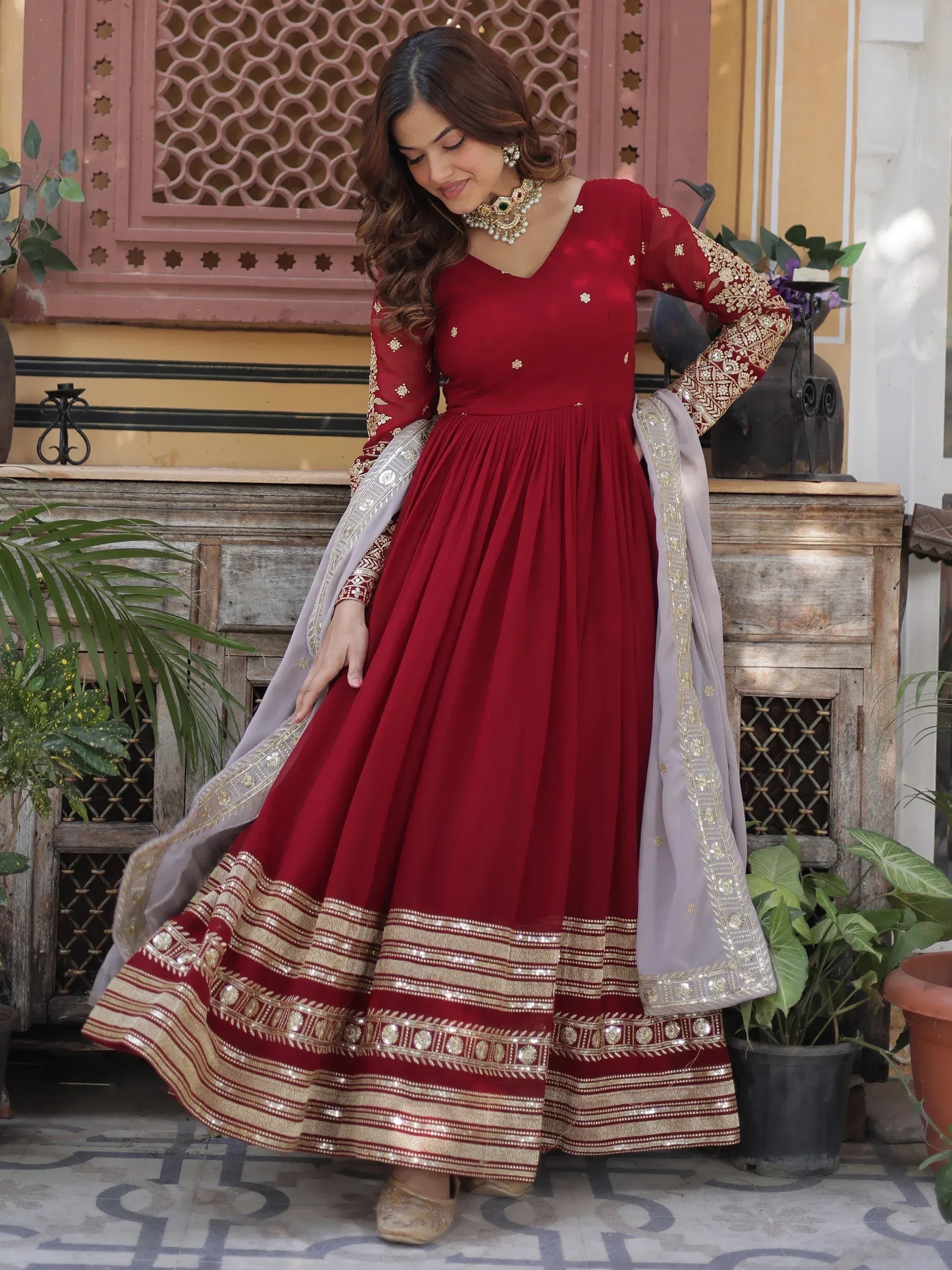 Woman wearing maroon embroidered Anarkali gown with gold accents and net dupatta