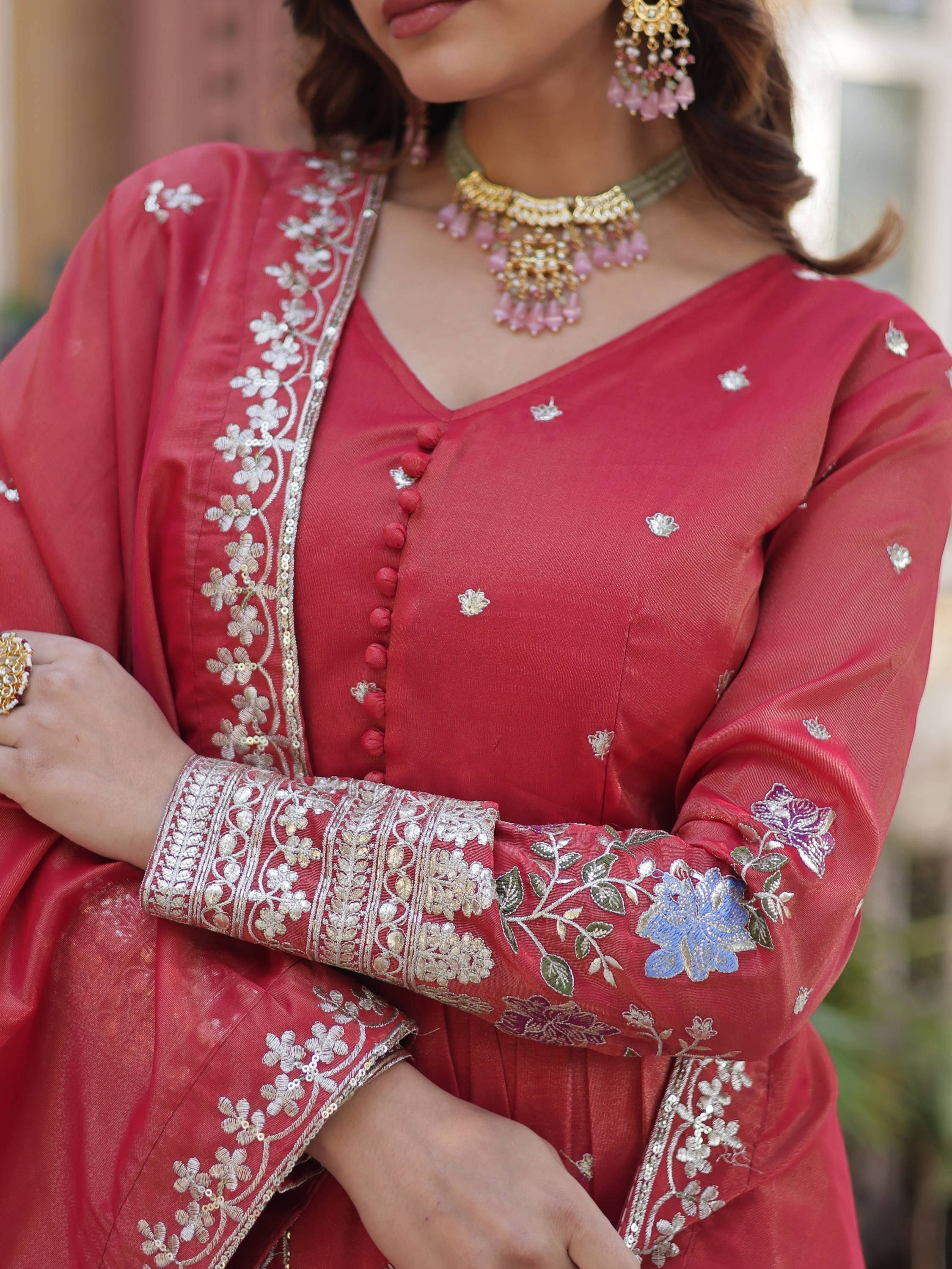 Red embroidered salwar kameez with floral detailing, paired with gold jewelry for ethnic wear