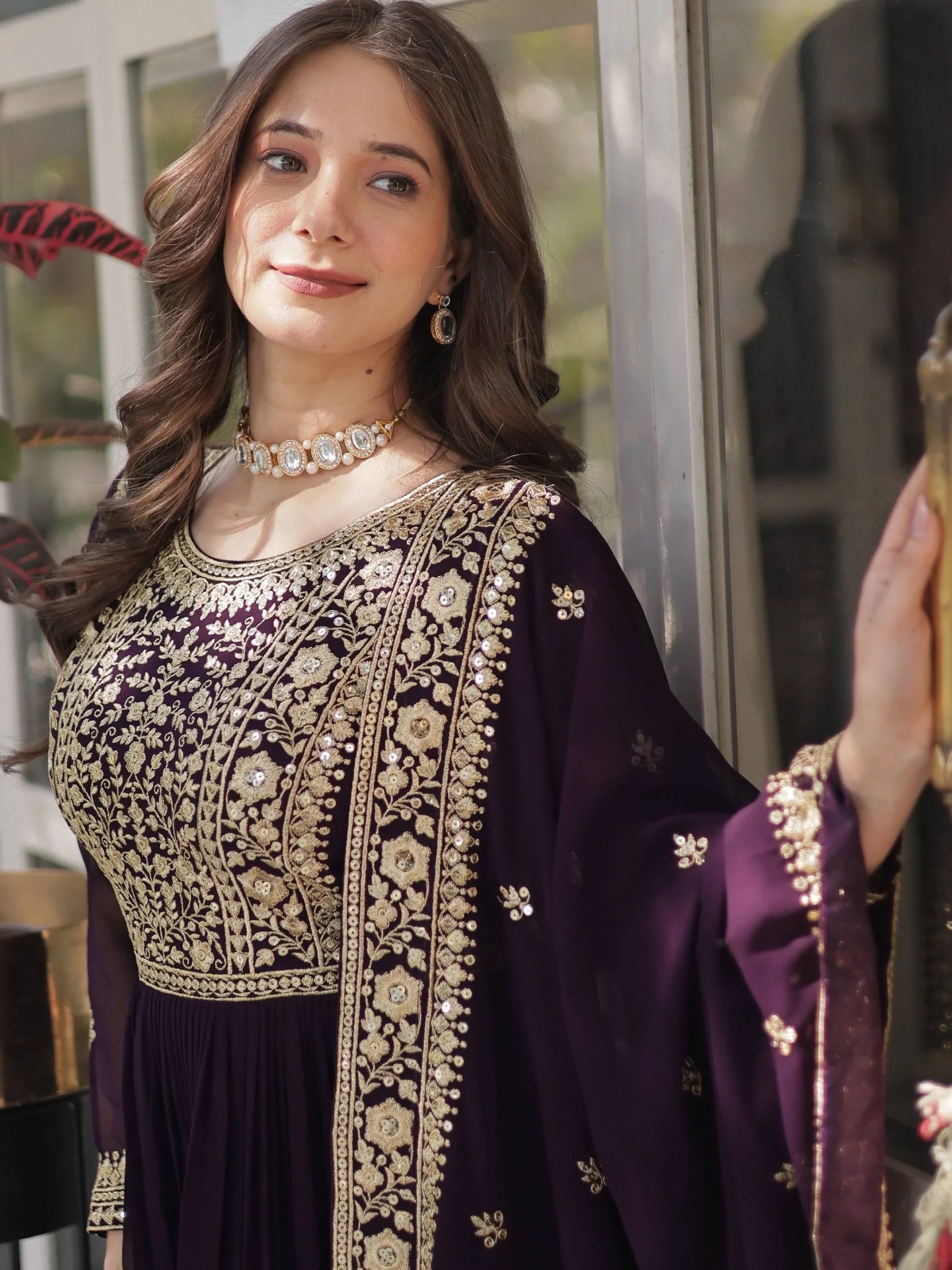 Woman wearing a wine purple embroidered ethnic gown with gold floral detailing