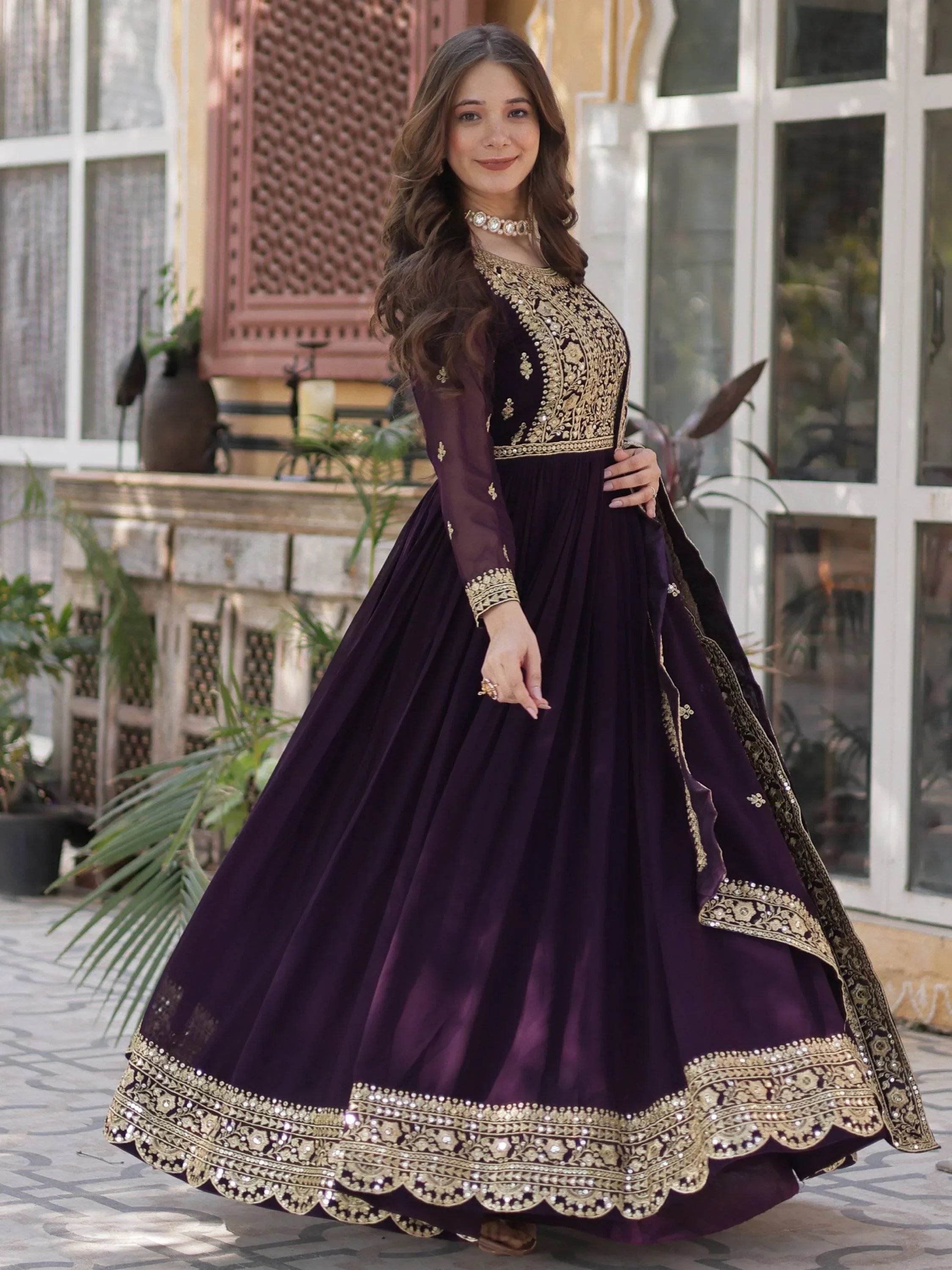 Woman in wine purple embroidered ethnic gown with gold detailing, outdoor setting
