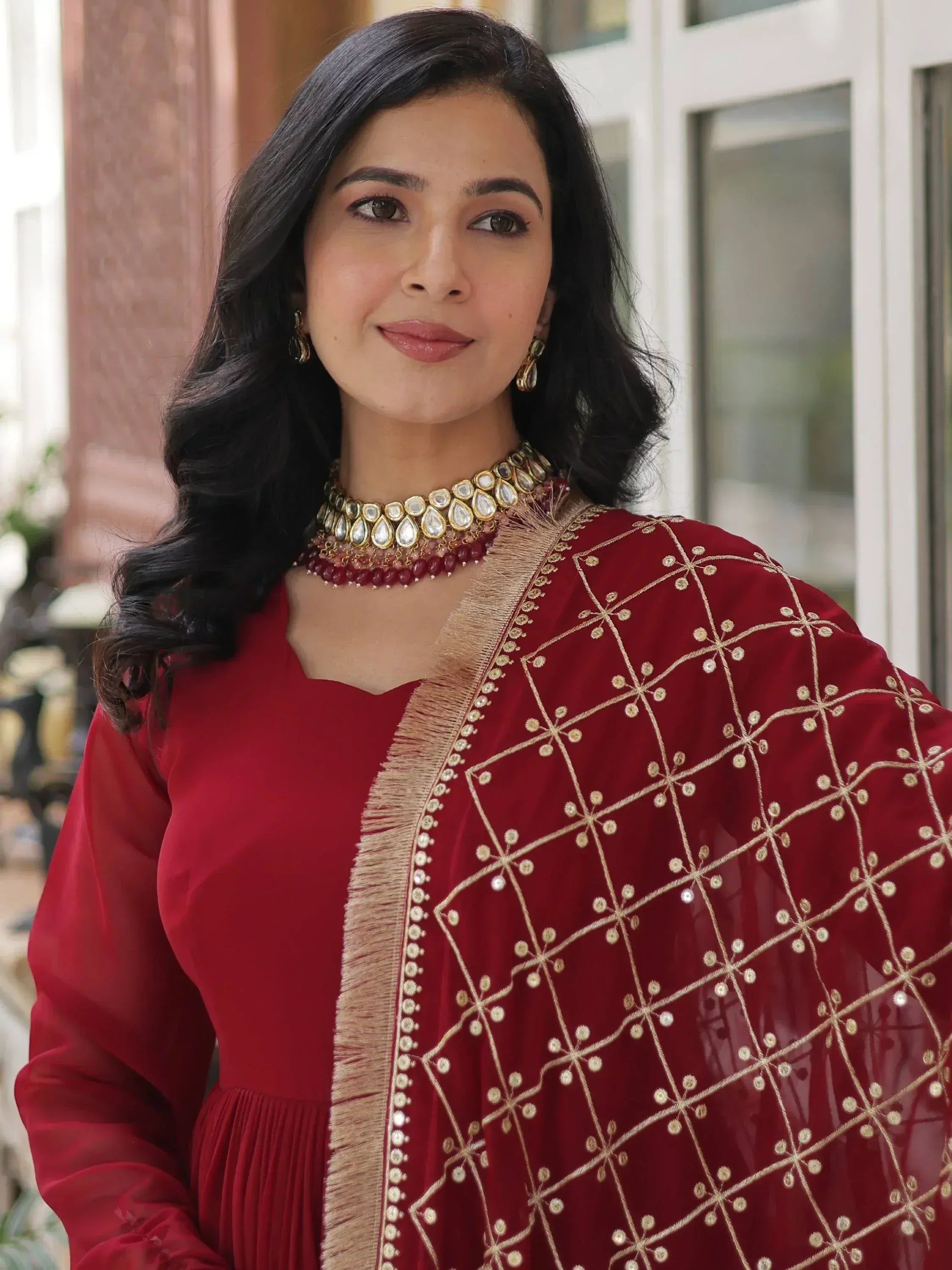 Woman in maroon ethnic gown with gold embroidery and traditional jewelry