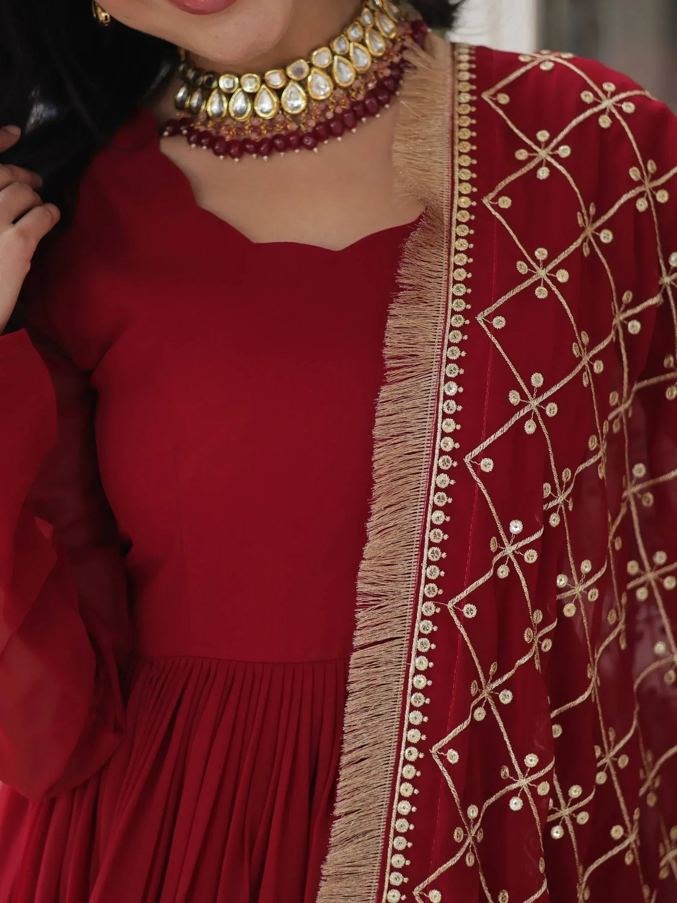 Red ethnic gown with gold embroidery and tassels, paired with traditional jewelry