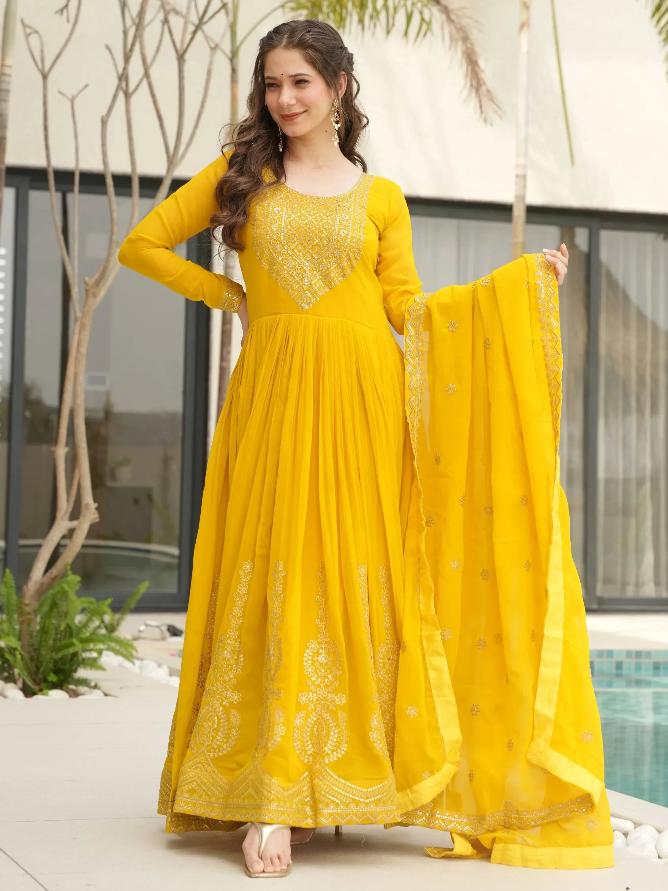 Woman wearing a yellow embroidered Anarkali suit with matching dupatta outdoors