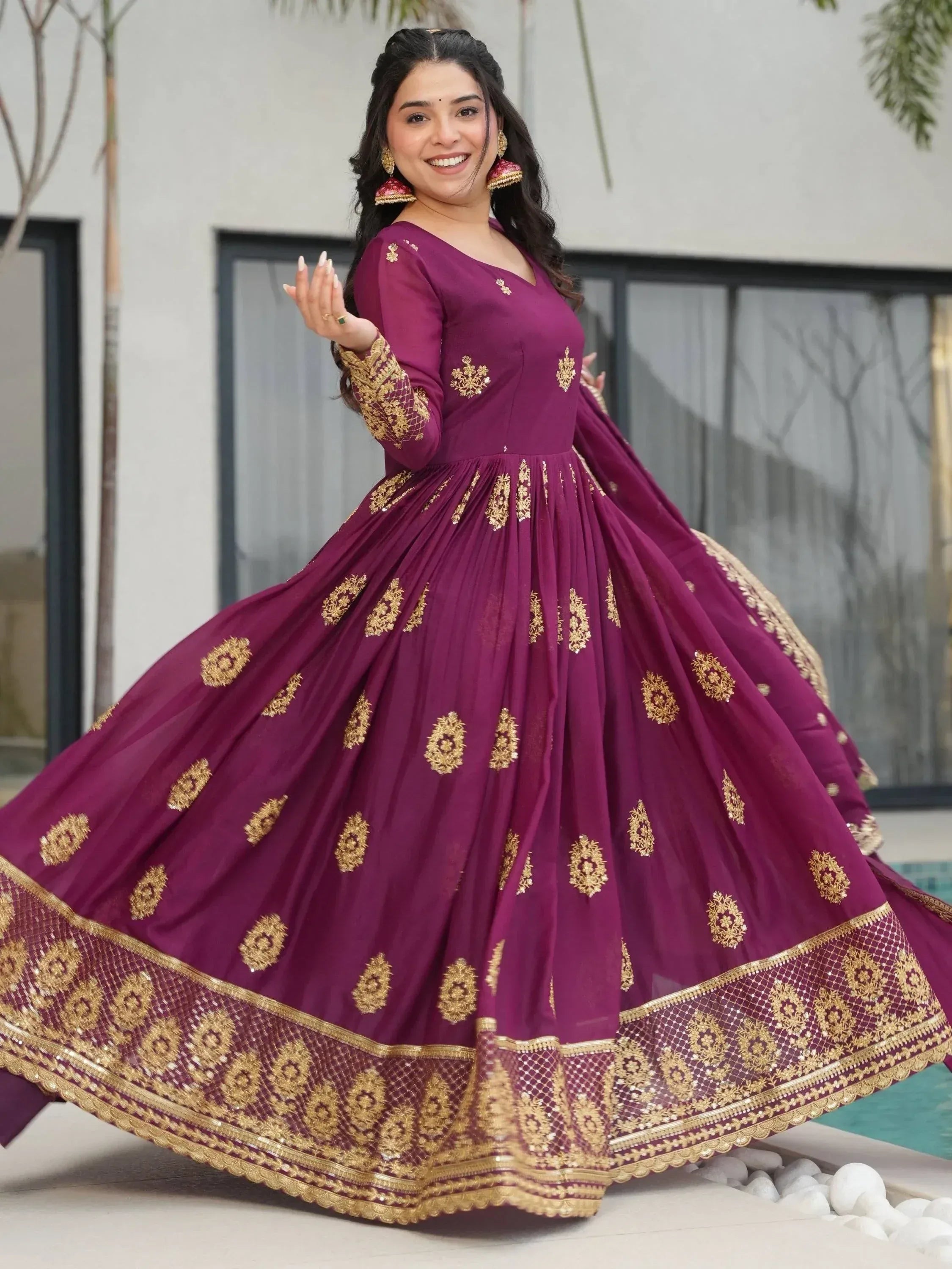 Woman in maroon ethnic gown with gold embroidery, perfect for Indian weddings and festive occasions