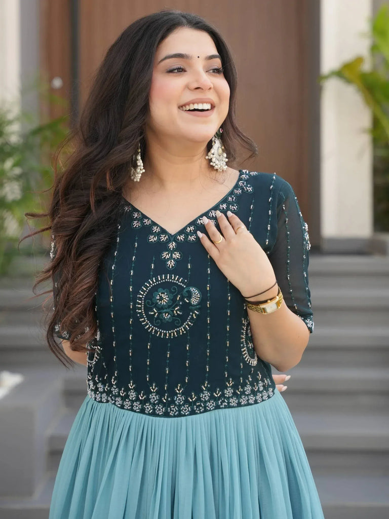 Woman in elegant teal ethnic gown with intricate beadwork and pleated skirt, perfect for Indian occasions.