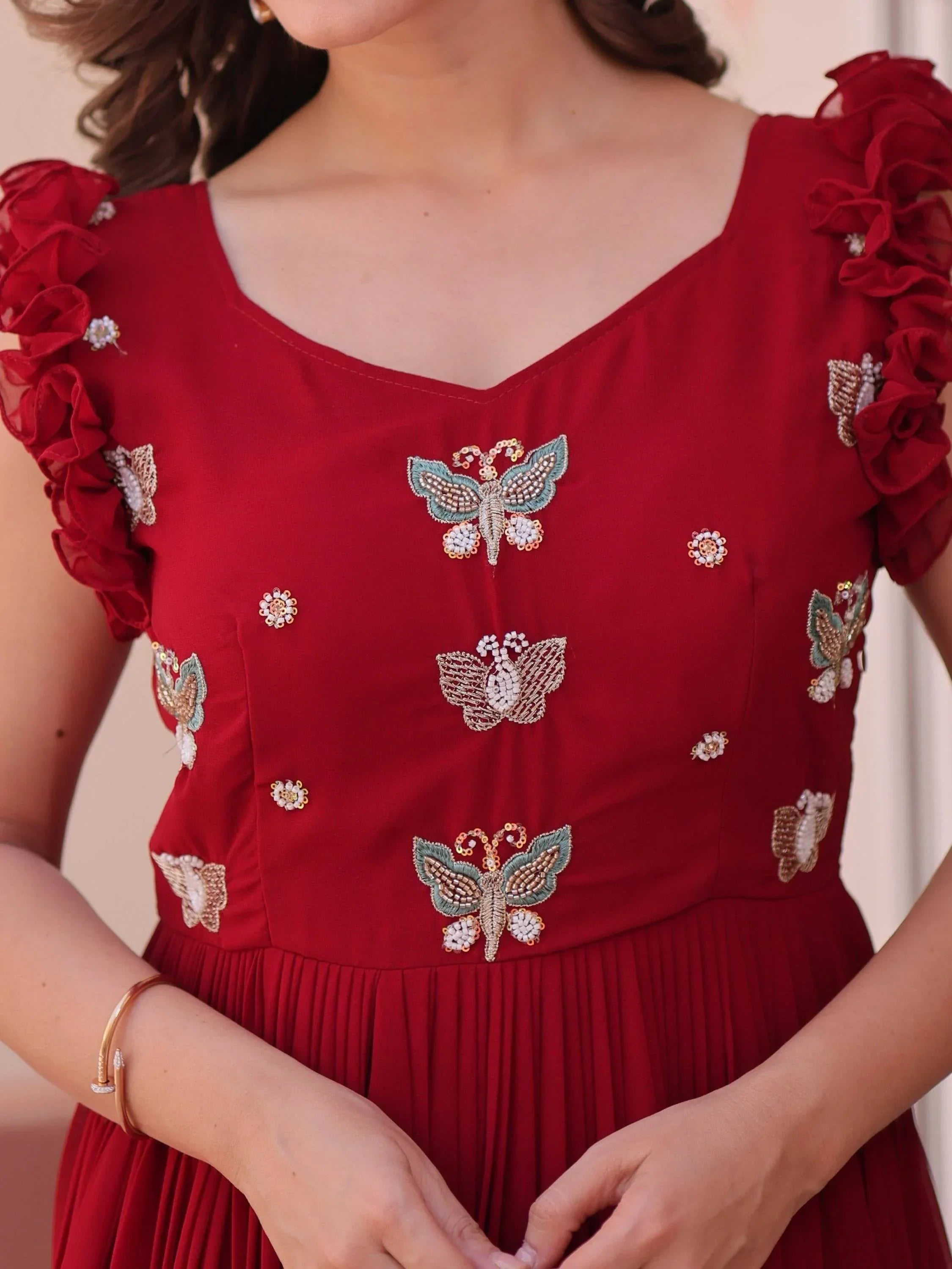 Maroon ethnic dress with butterfly embroidery and ruffled sleeves, close-up view