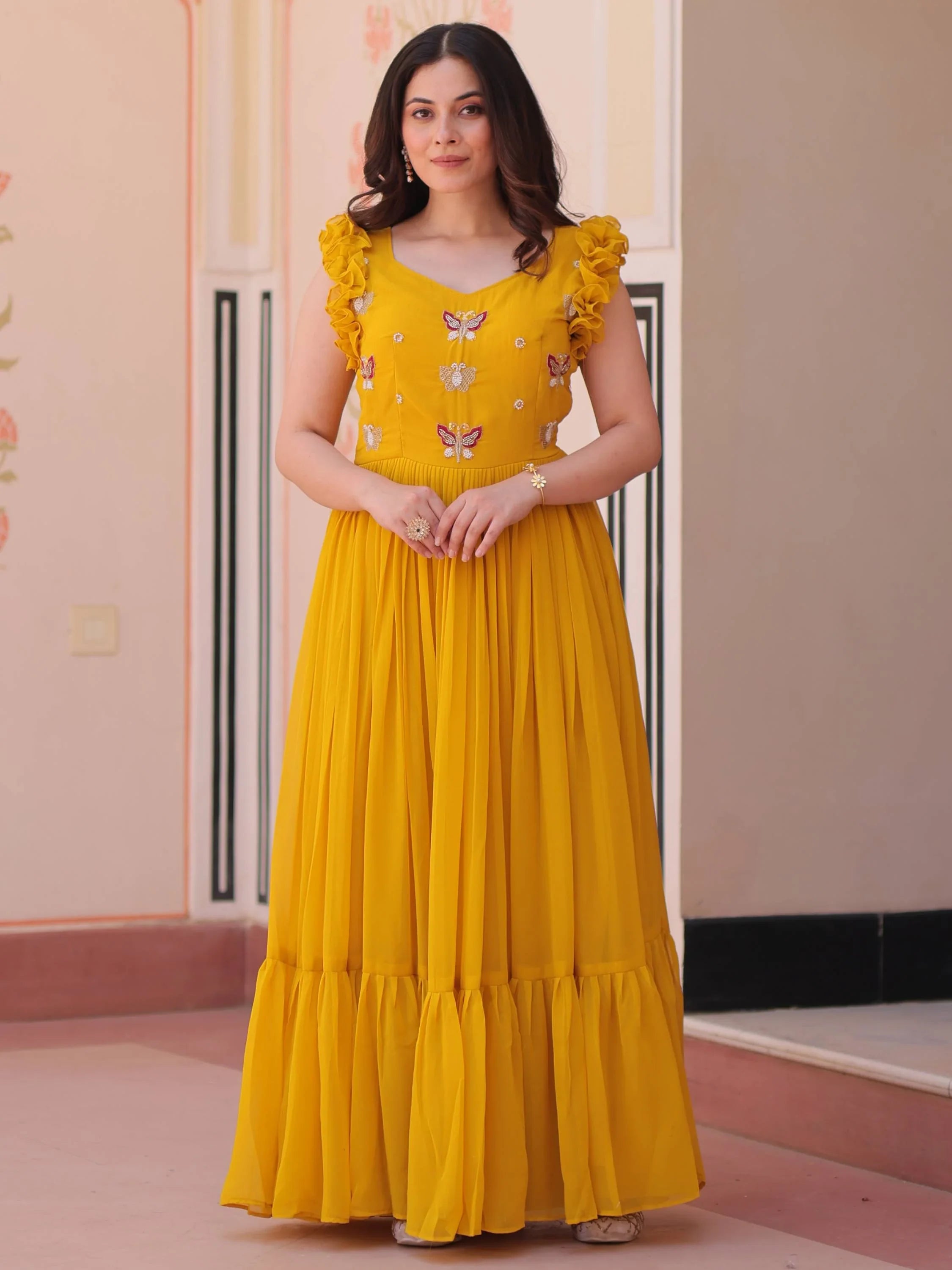 Woman in a yellow embroidered ethnic gown with butterfly motifs and ruffled sleeves