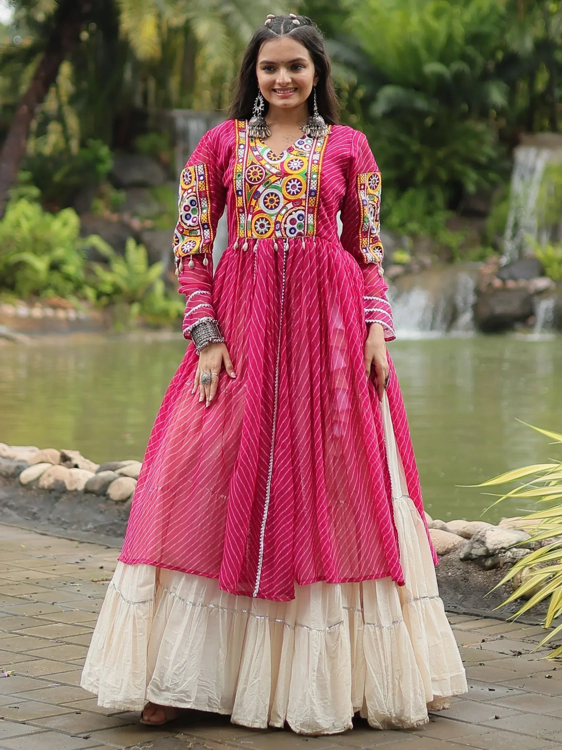 Vibrant pink ethnic gown with colorful embroidery and layered skirt, perfect for festive occasions.