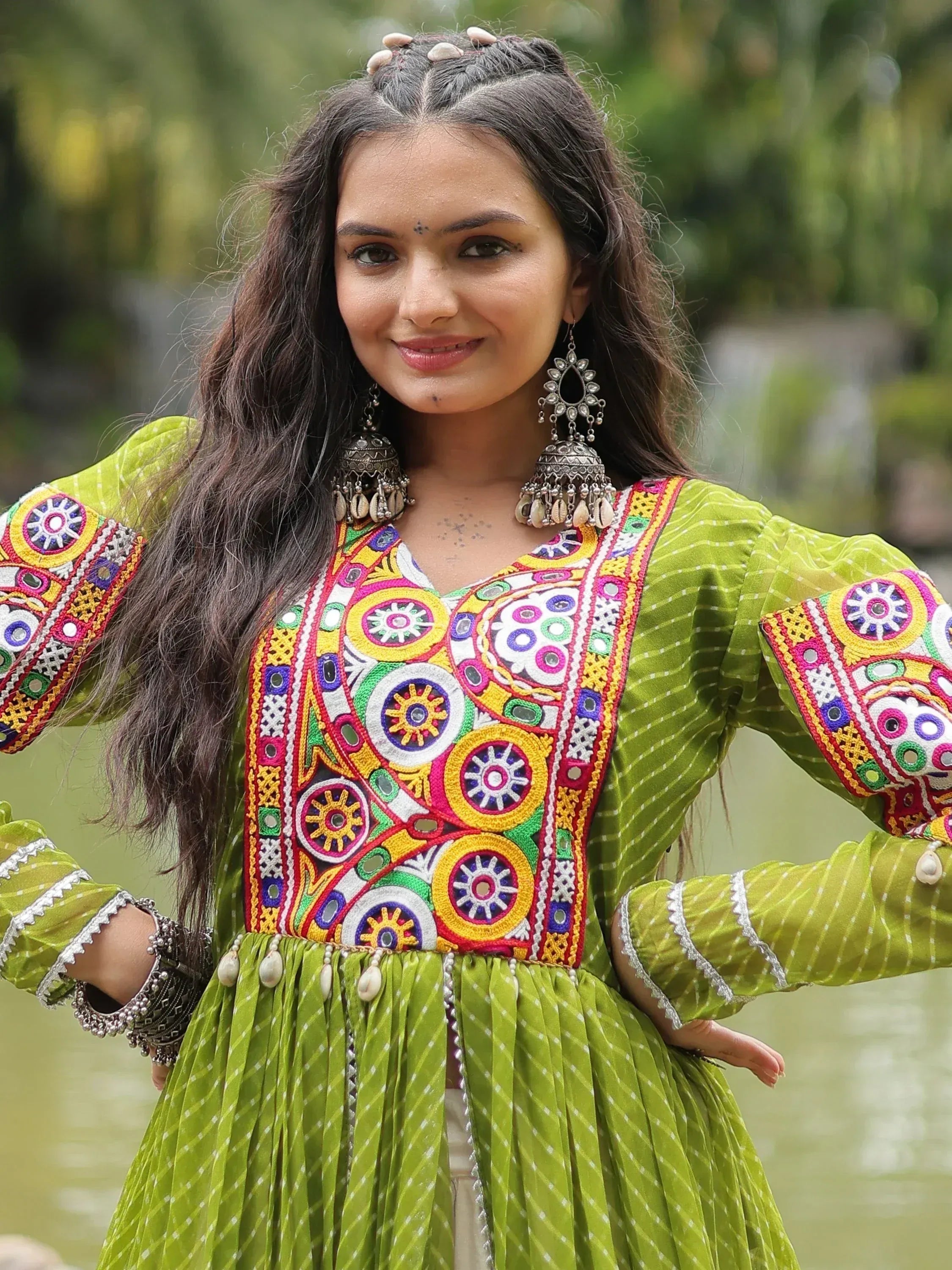 Woman in vibrant green ethnic dress with colorful mirror embroidery and traditional jewelry
