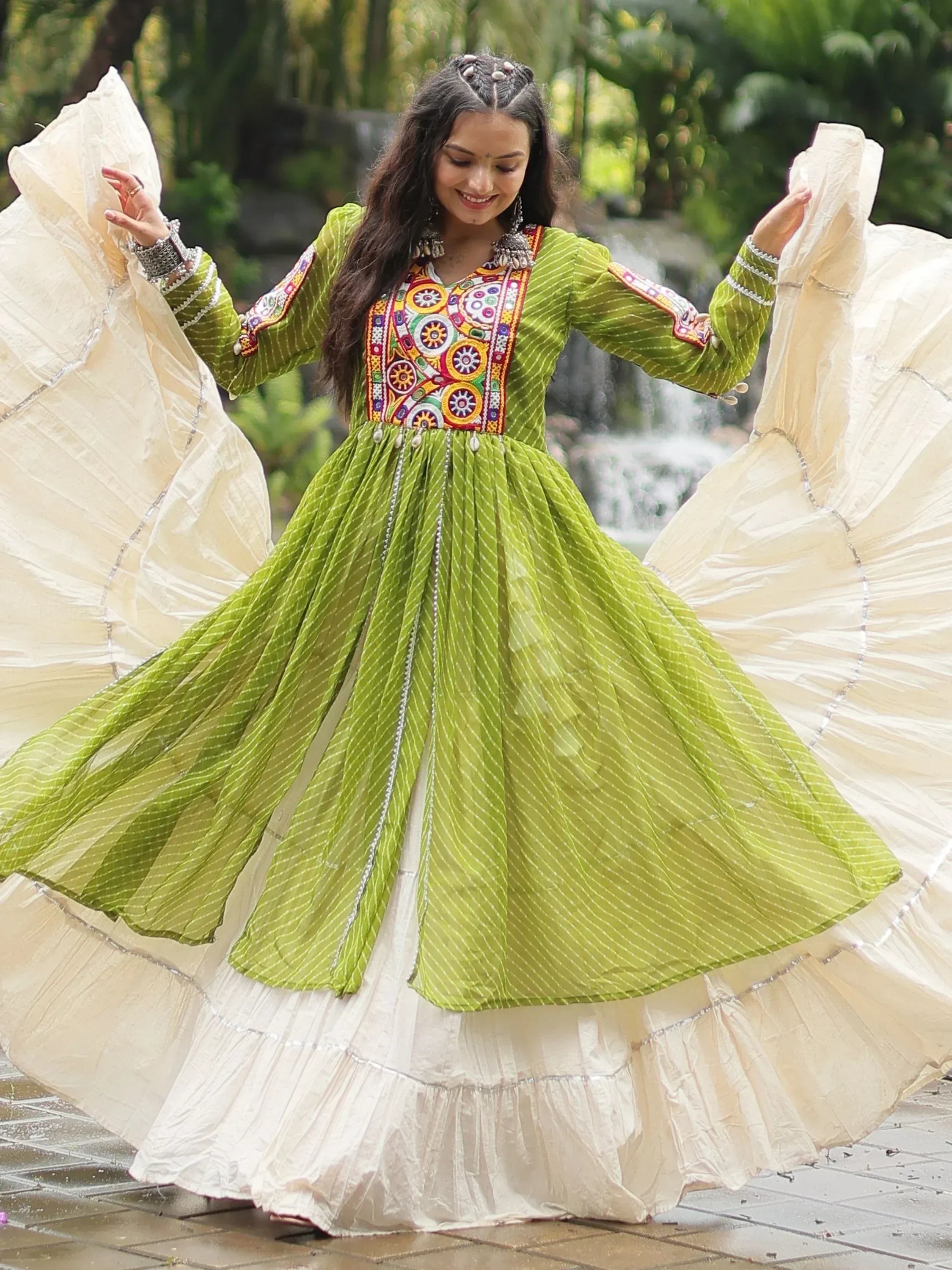 Woman twirling in vibrant green embroidered ethnic gown with white flared skirt, perfect for festive occasions.