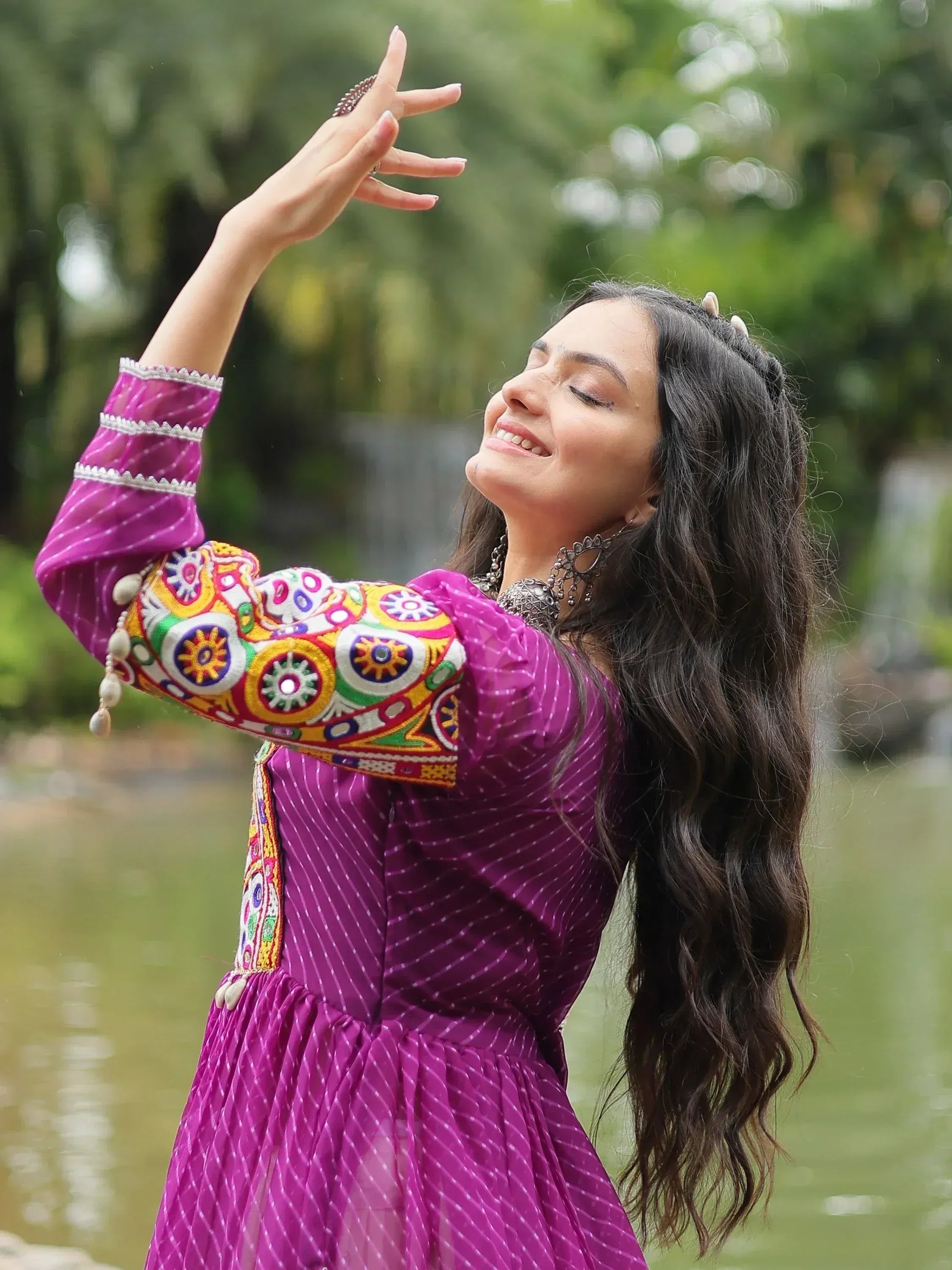 Woman in traditional purple embroidered ethnic dress with long hair by a pond outdoors