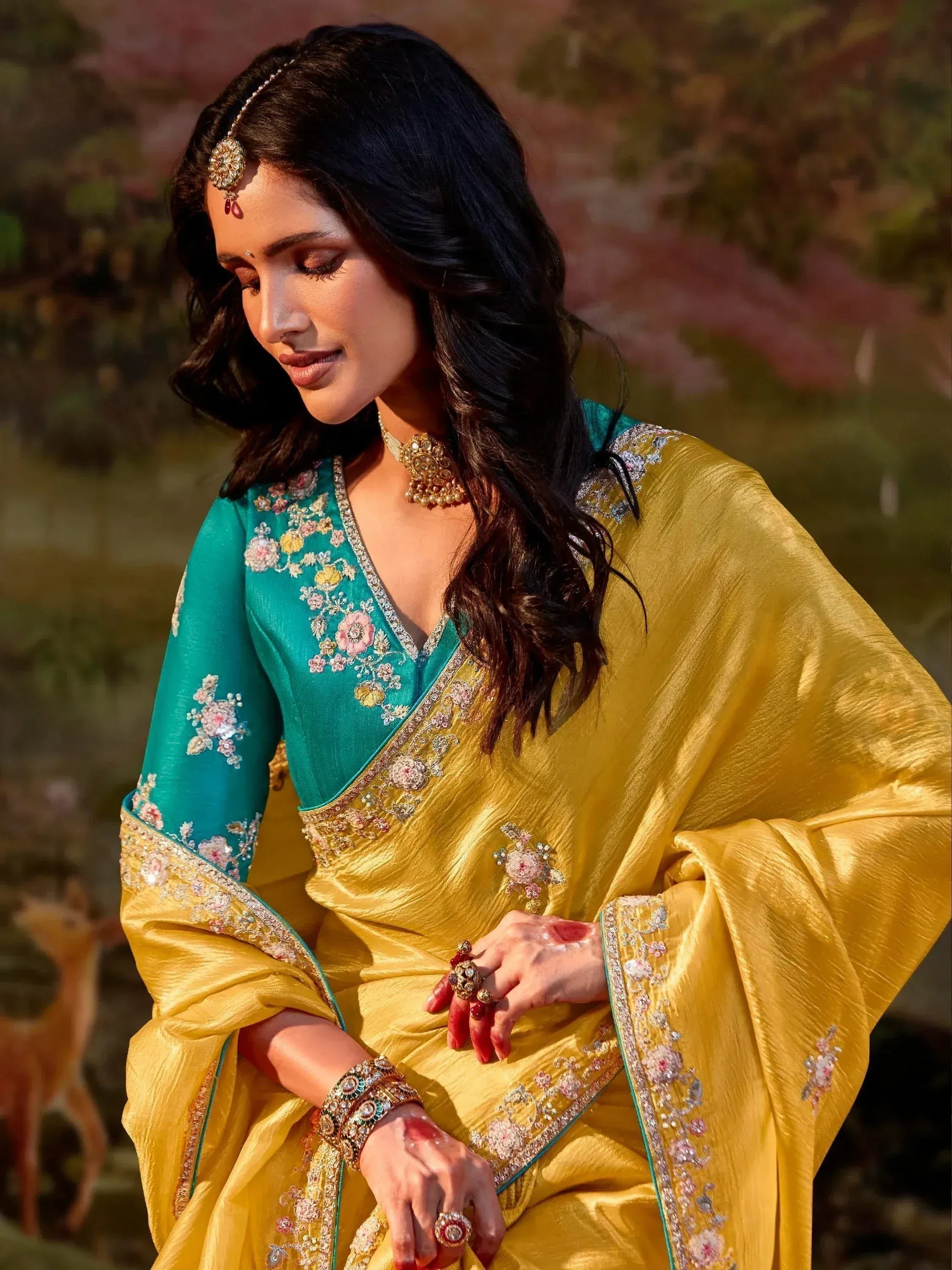 Woman in elegant teal and gold embroidered saree with floral details, traditional Indian ethnic wear