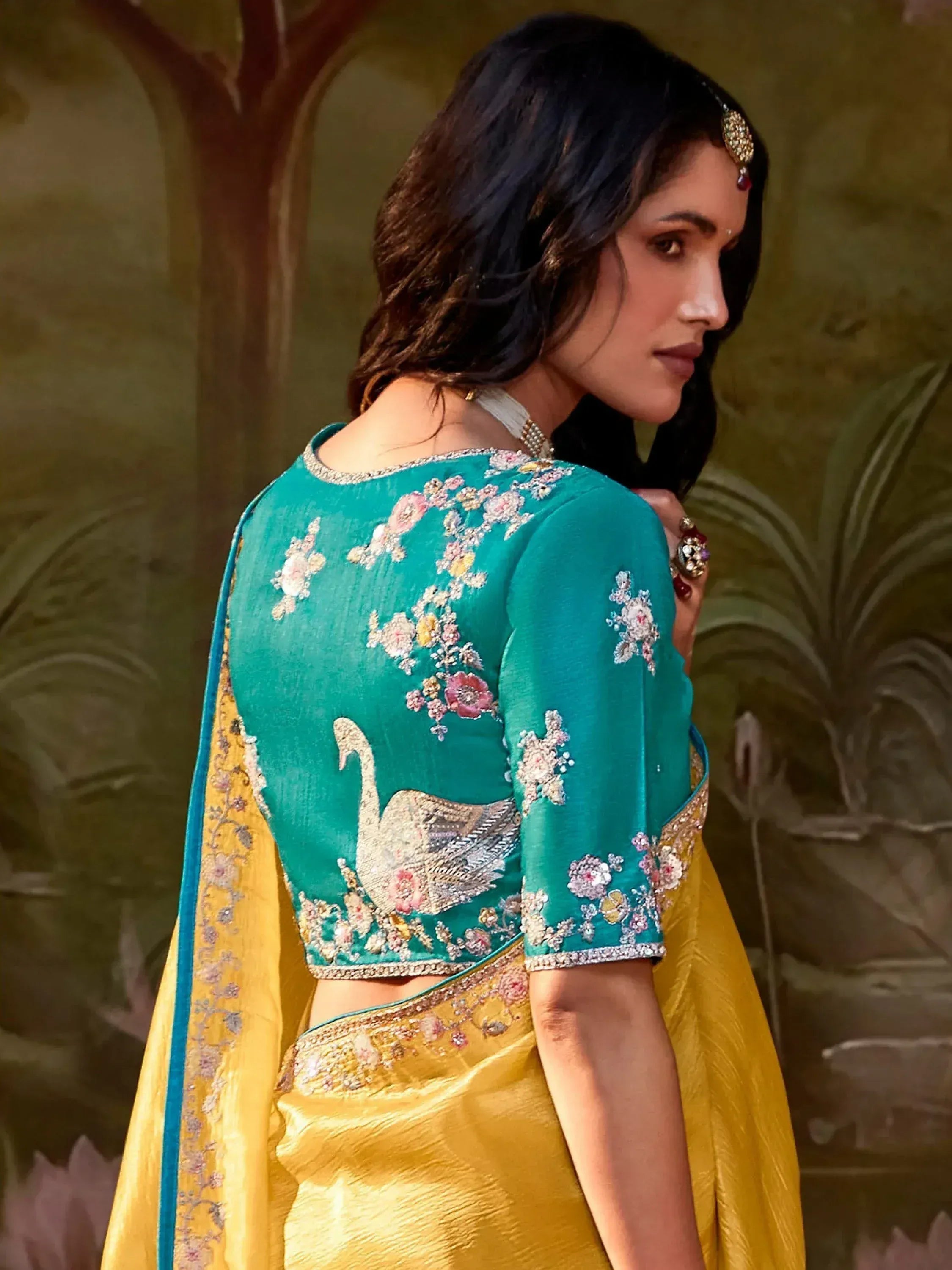 Teal embroidered blouse with swan motif, paired with yellow saree, perfect for Indian ethnic wear occasions