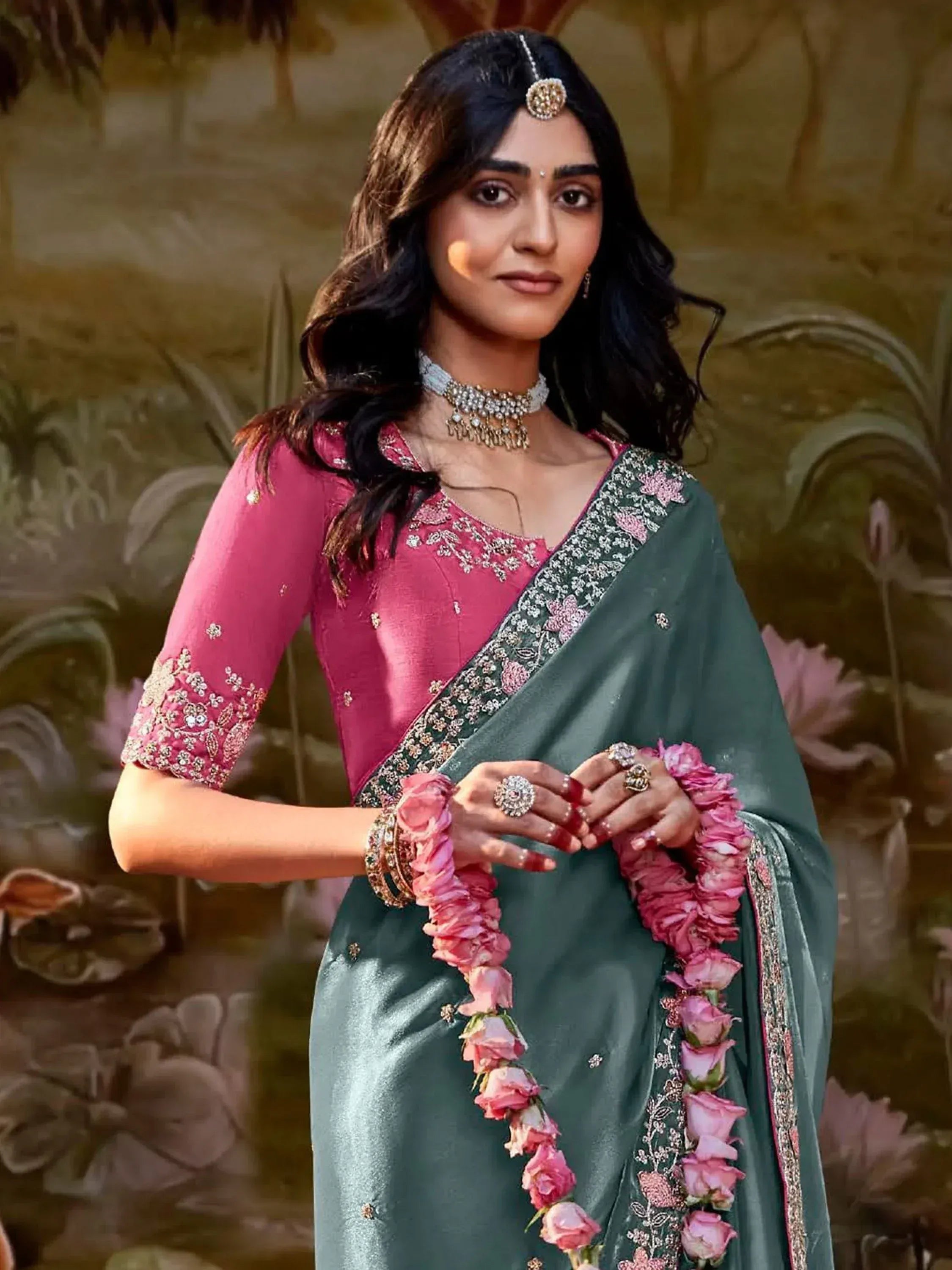 Woman in pink embroidered blouse and green saree with floral border, traditional Indian ethnic wear