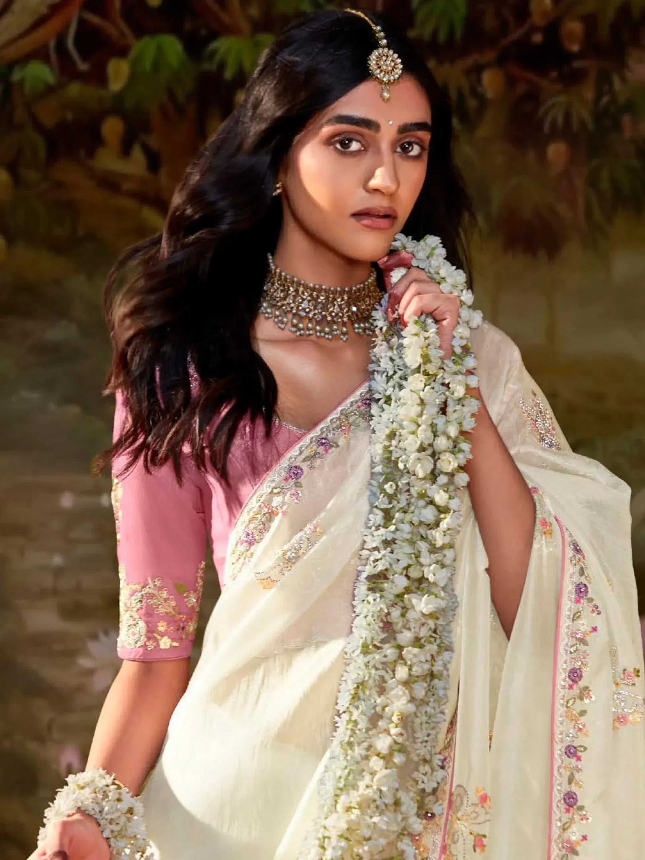 Woman in elegant white saree with pink blouse, floral embroidery, and traditional jewelry for Indian ethnic wear