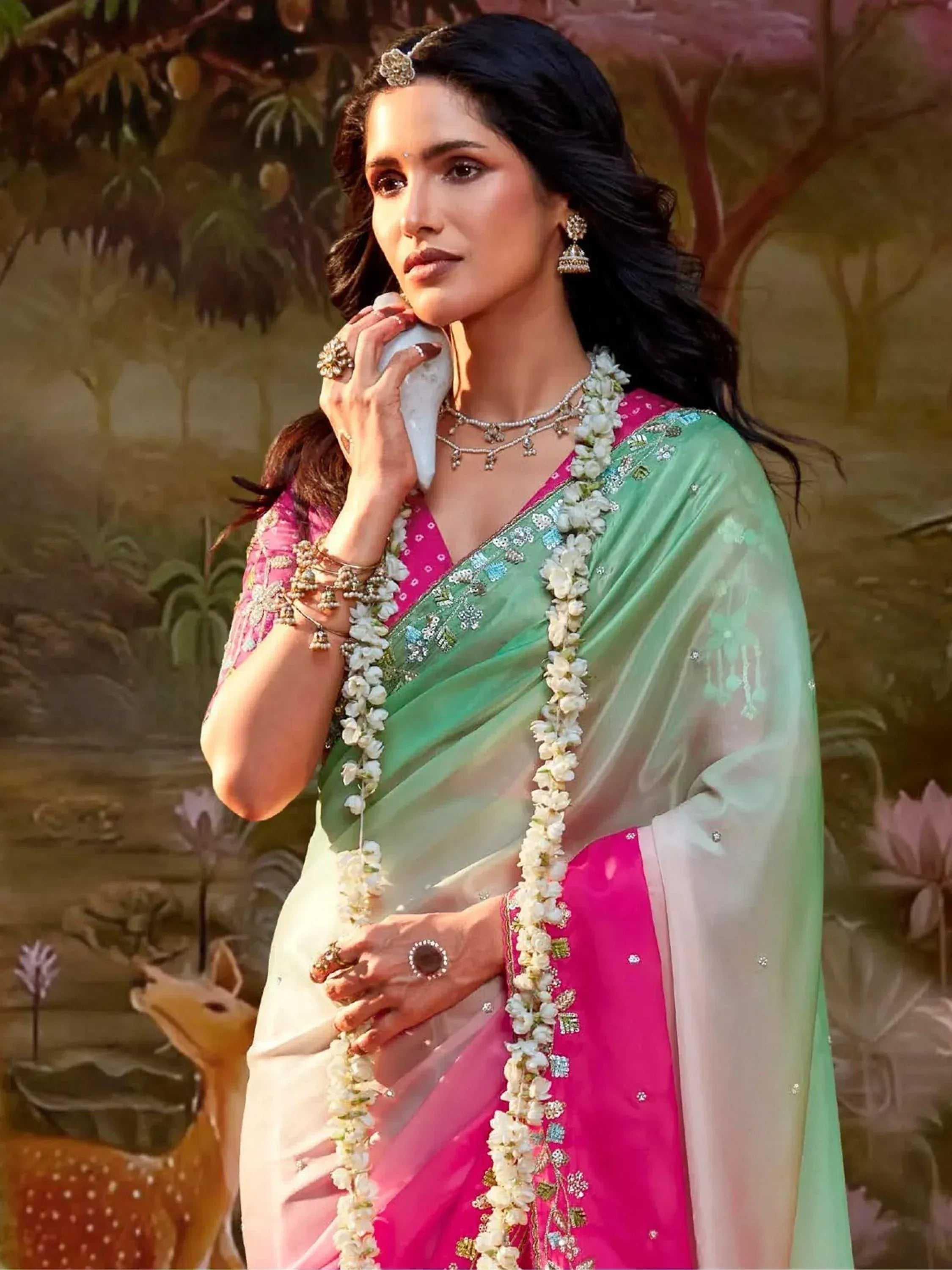 Woman in pink and green embroidered saree with floral garland, traditional Indian ethnic wear