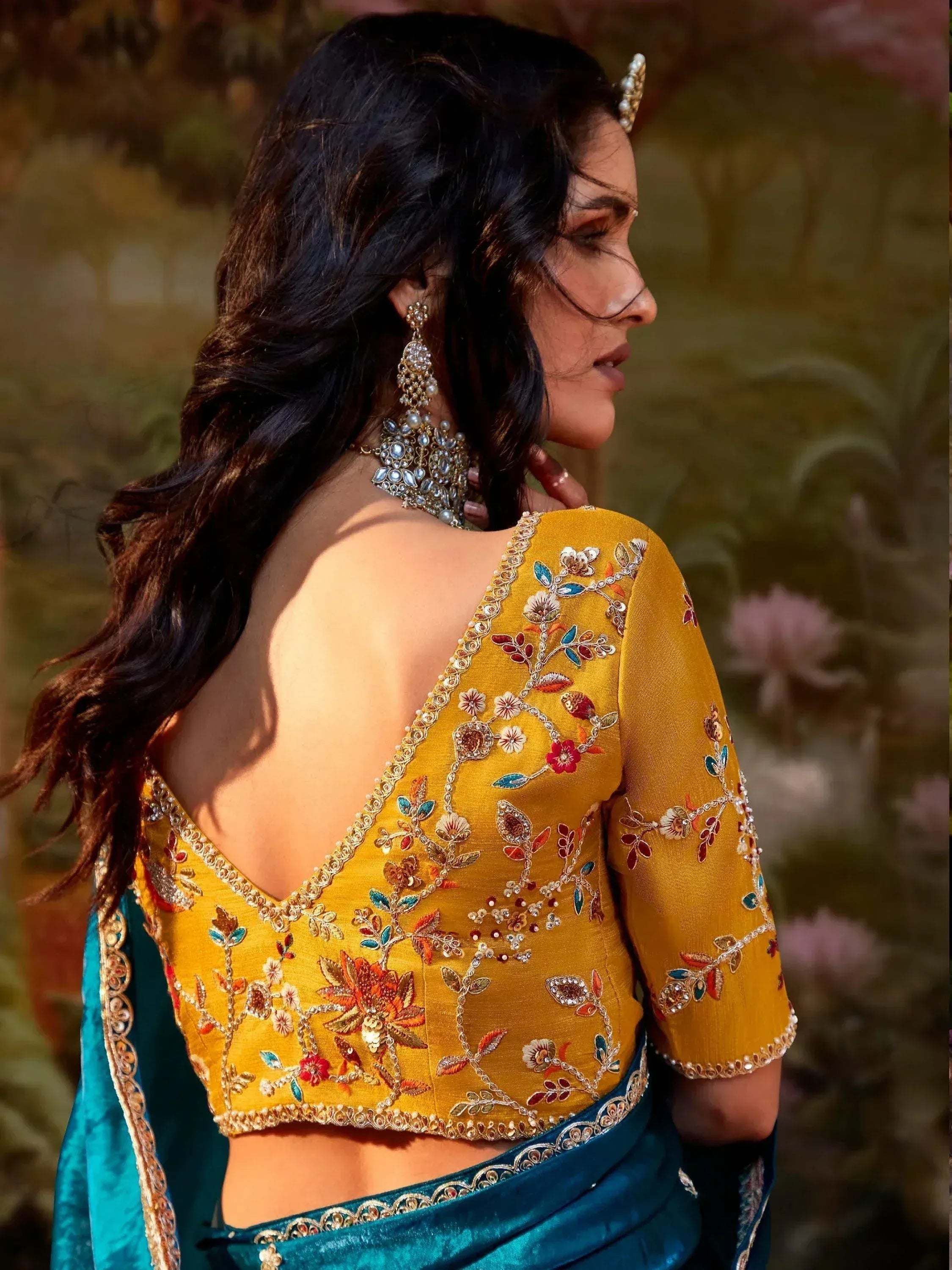Yellow floral embroidered blouse with open back, paired with teal saree, perfect for Indian ethnic wear