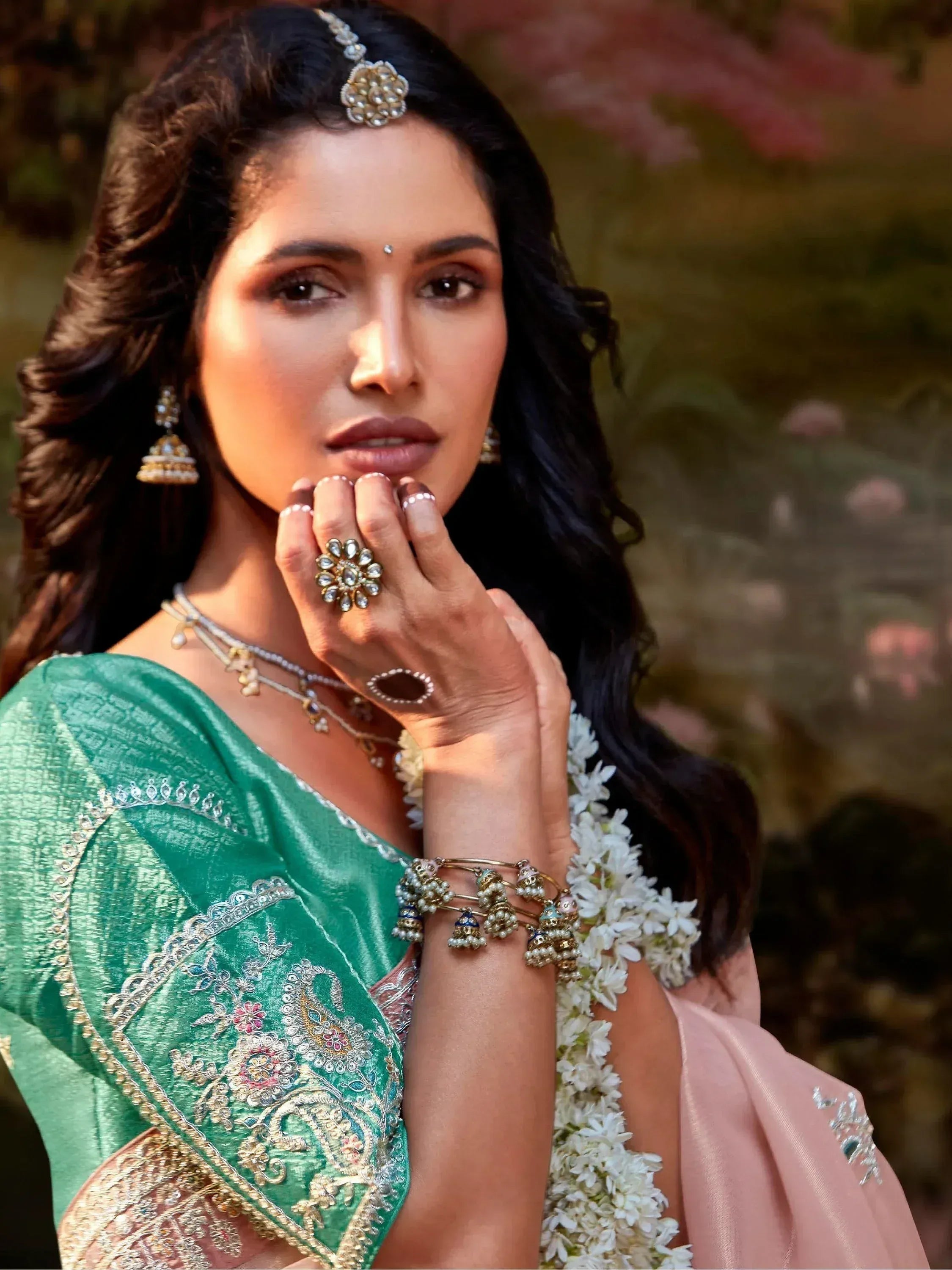 Elegant woman in green embroidered saree with floral jewelry, perfect for Indian ethnic wear occasions.