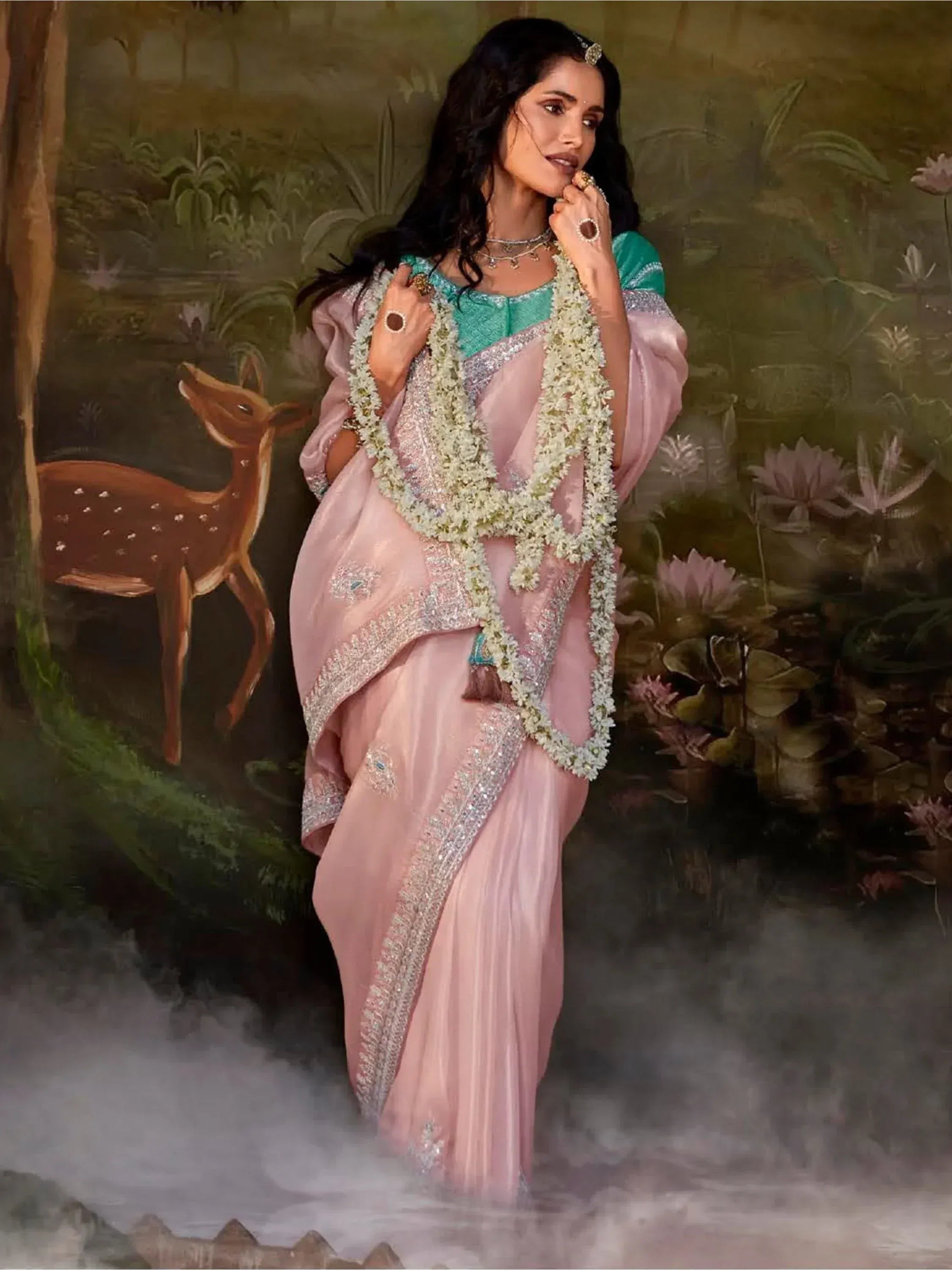 Elegant pink saree with silver embroidery, floral garland, and teal blouse, styled for Indian ethnic wear