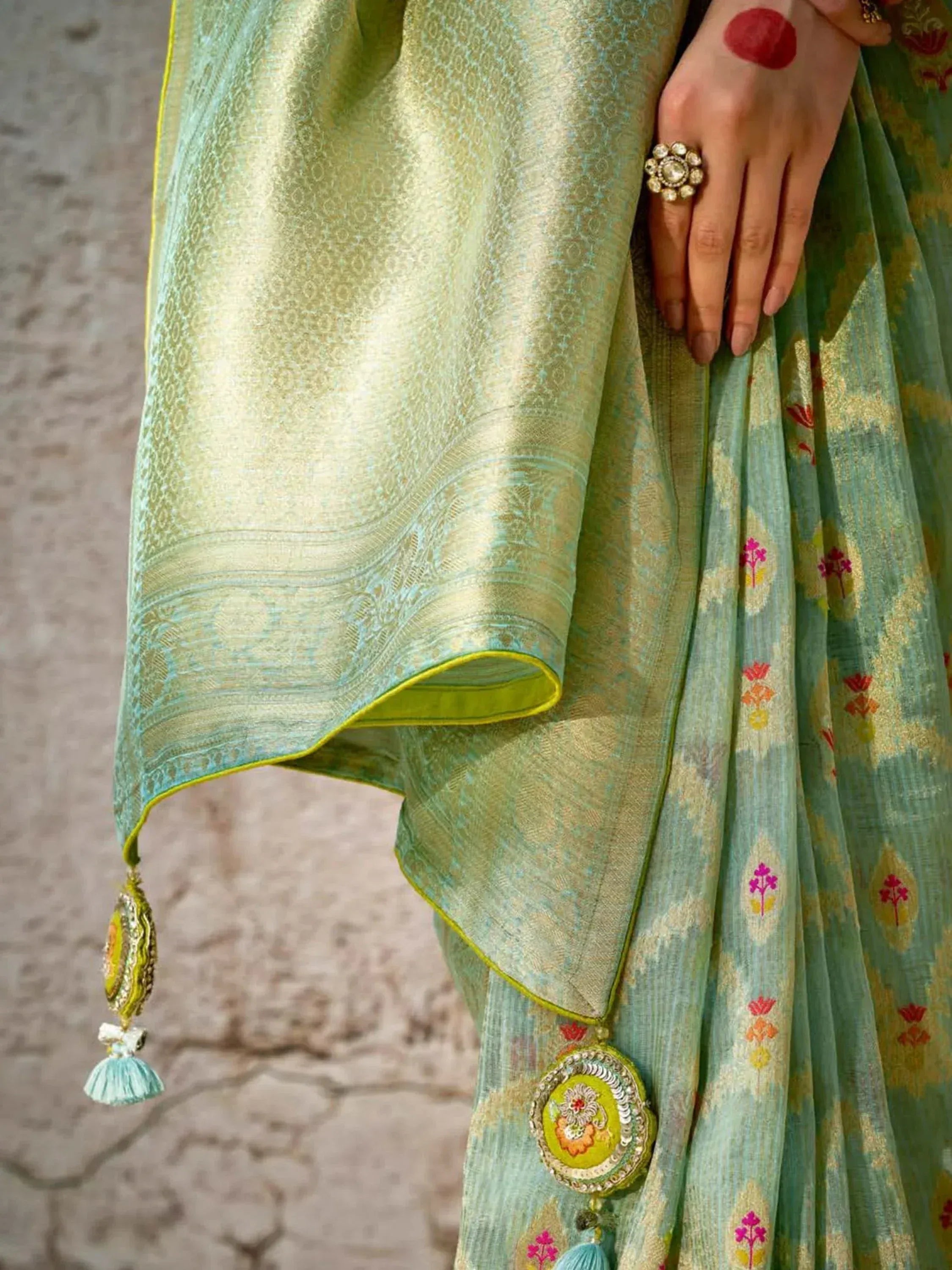 Elegant green ethnic saree with floral embroidery, gold zari, and tassel details for Indian occasions