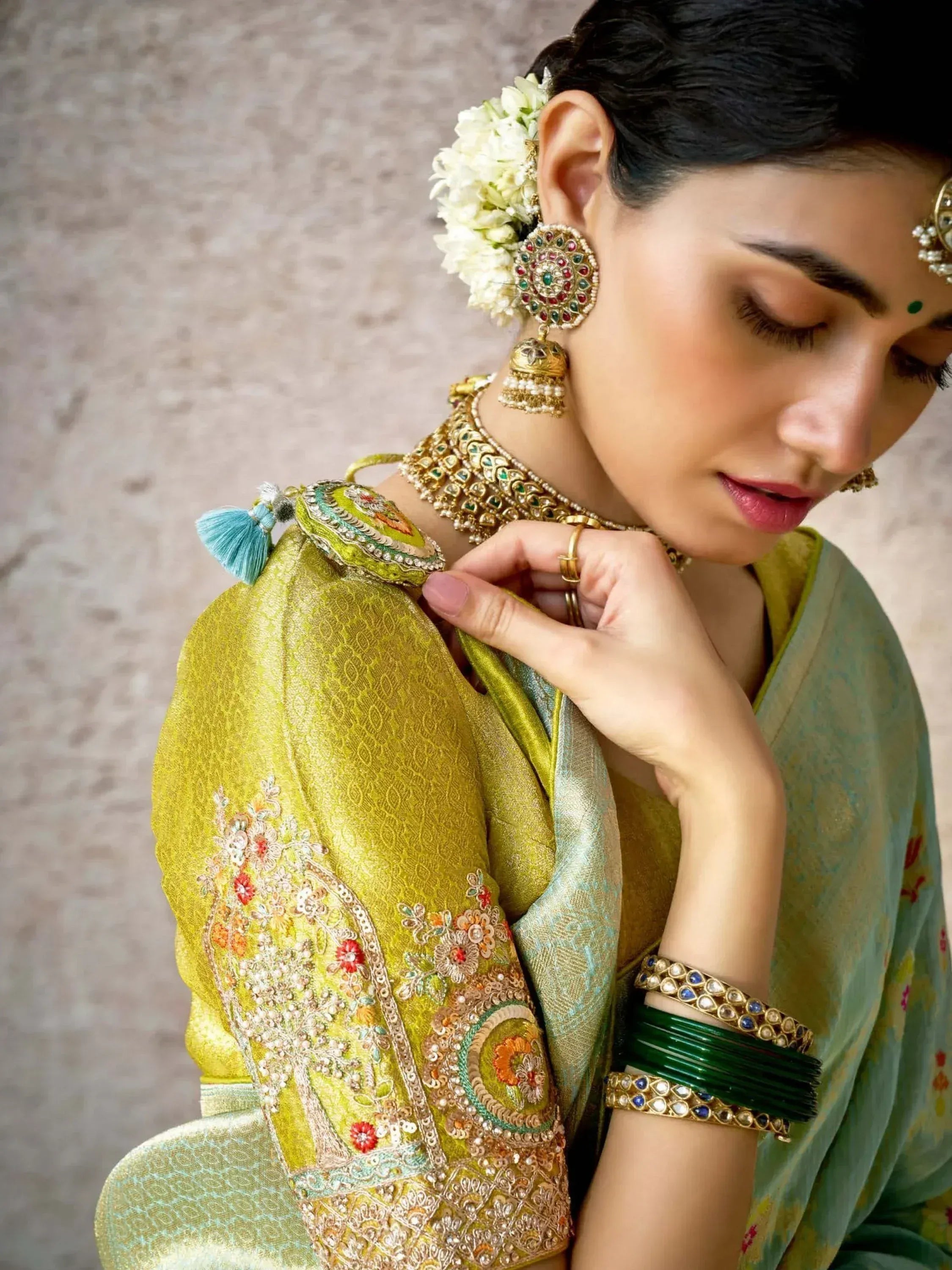 Woman in embroidered green lehenga choli with floral jewelry and bangles, Indian ethnic wear