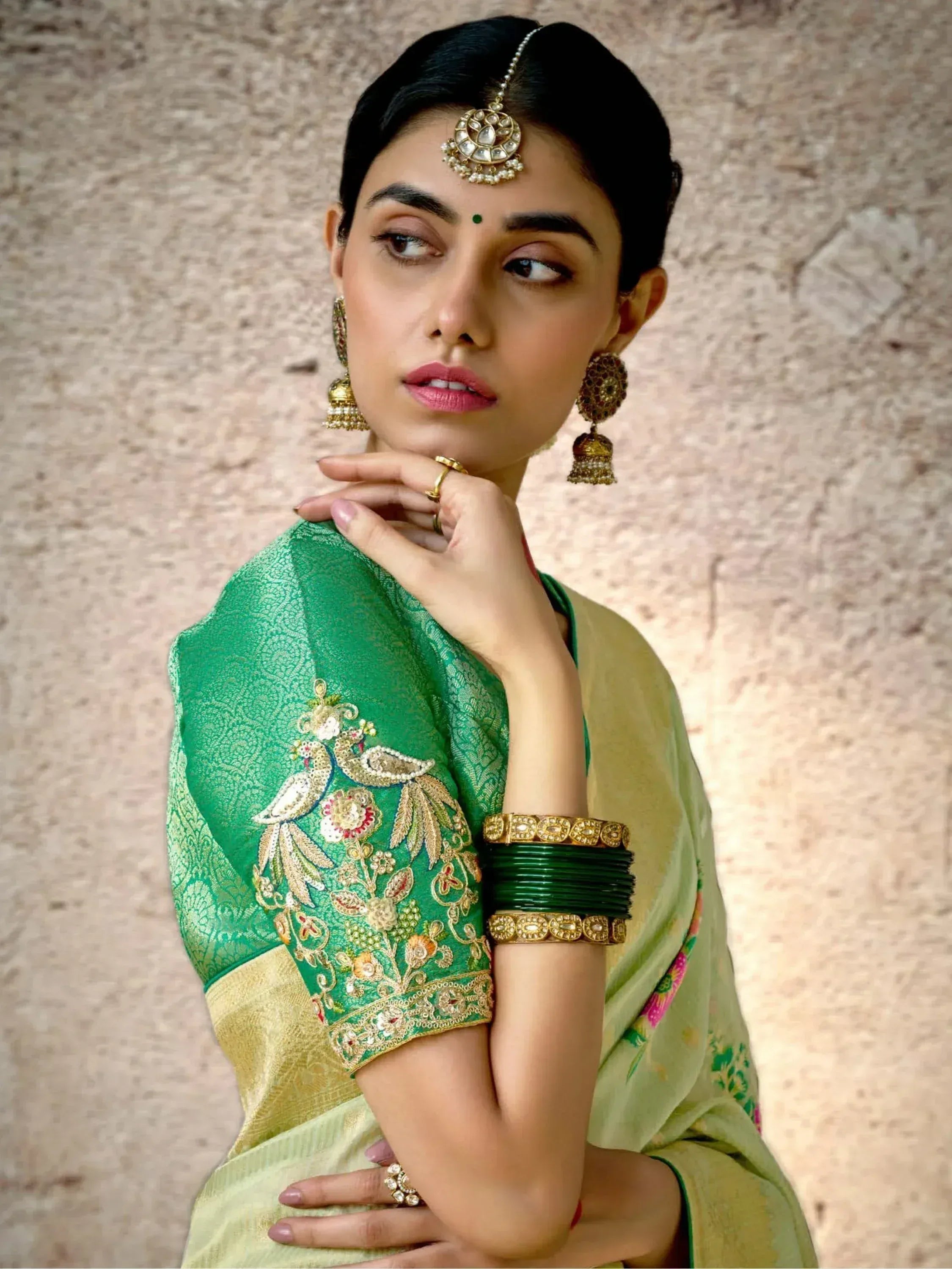 Elegant green saree with peacock embroidery, gold jewelry, and traditional Indian bridal accessories