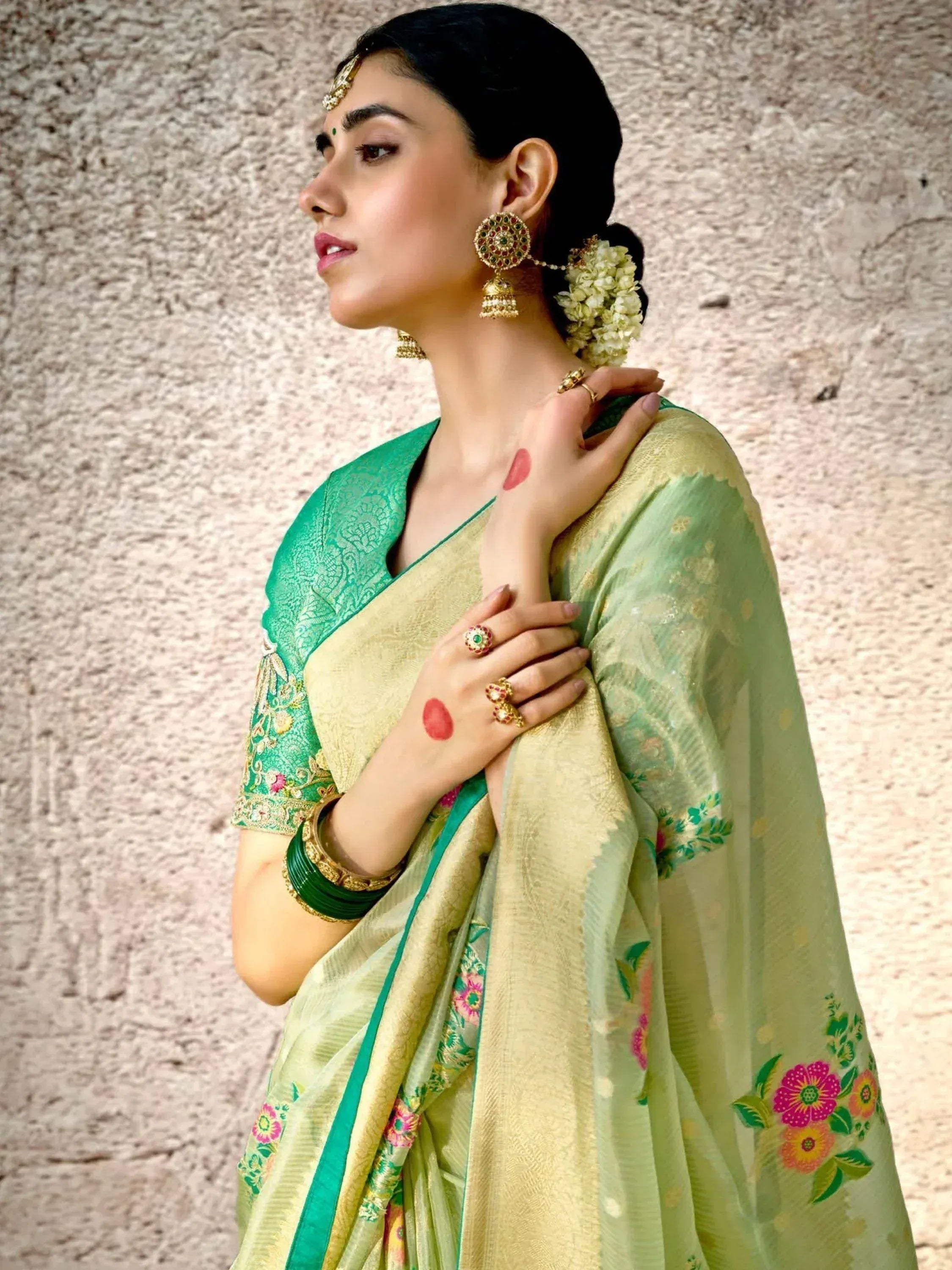 Woman in elegant green and gold floral saree with traditional jewelry, perfect for Indian ethnic wear occasions
