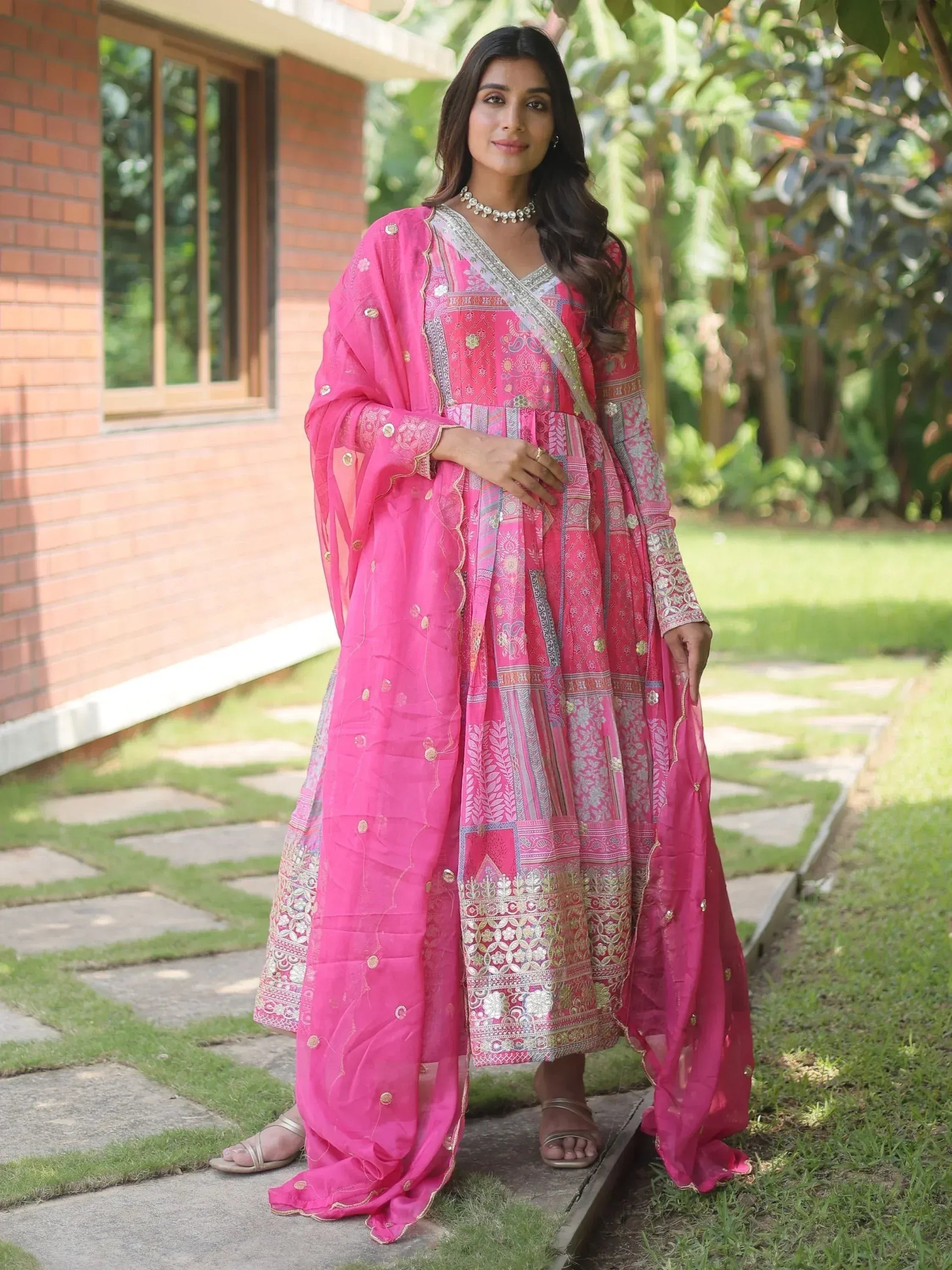 Woman in vibrant pink ethnic anarkali suit with intricate embroidery, perfect for Indian festive occasions