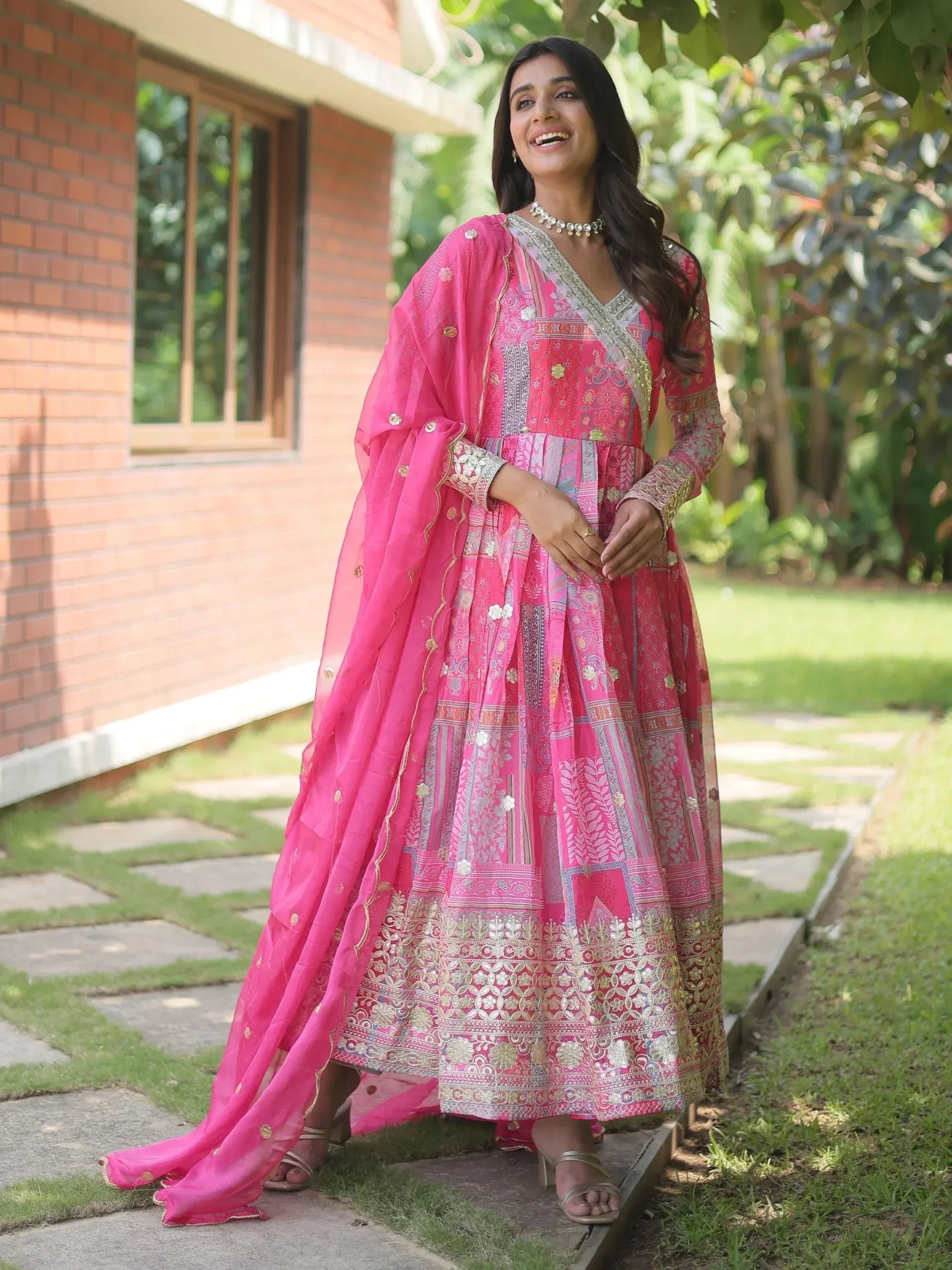Woman in vibrant pink ethnic anarkali suit with gold embroidery, perfect for Indian occasions and festivals