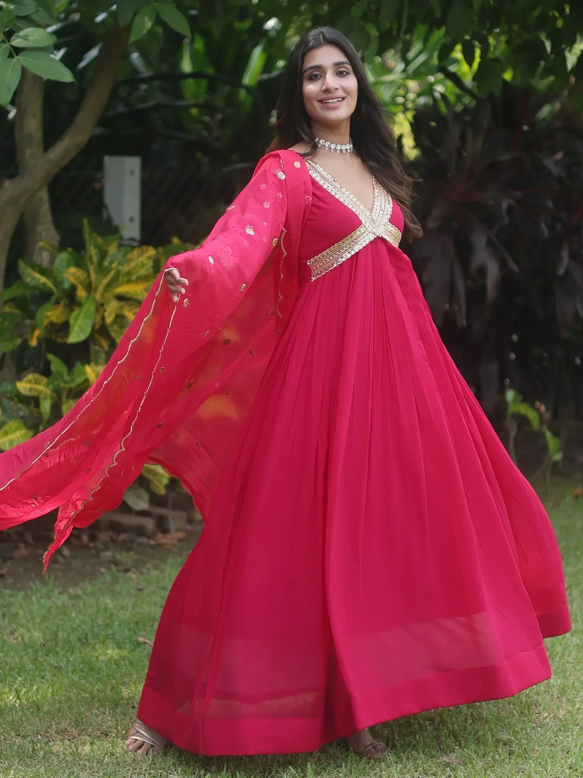 Woman in vibrant pink ethnic gown with gold embroidery, perfect for Indian celebrations and festive occasions.