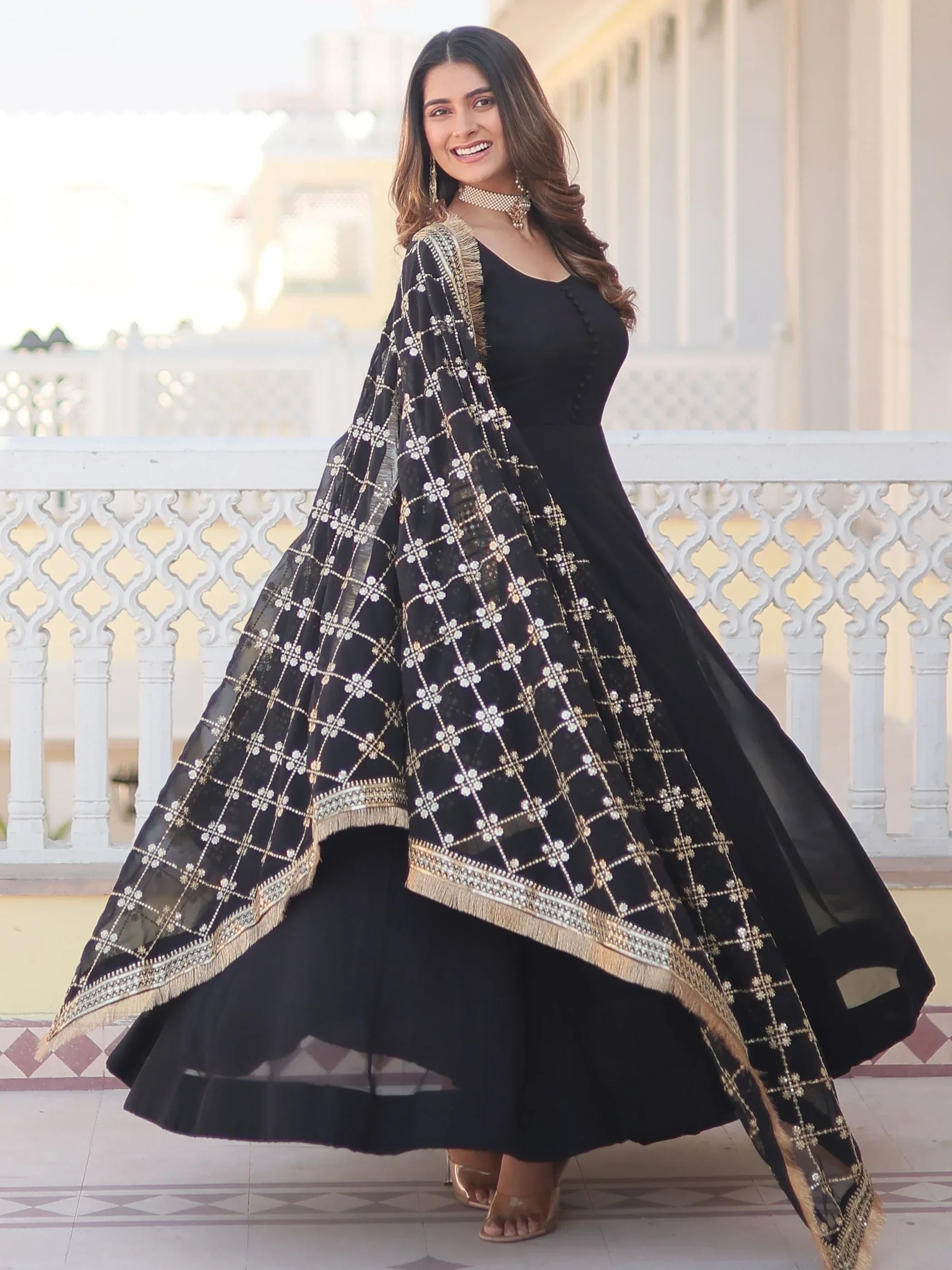 Woman wearing black ethnic gown with gold embroidered dupatta, posing outdoors