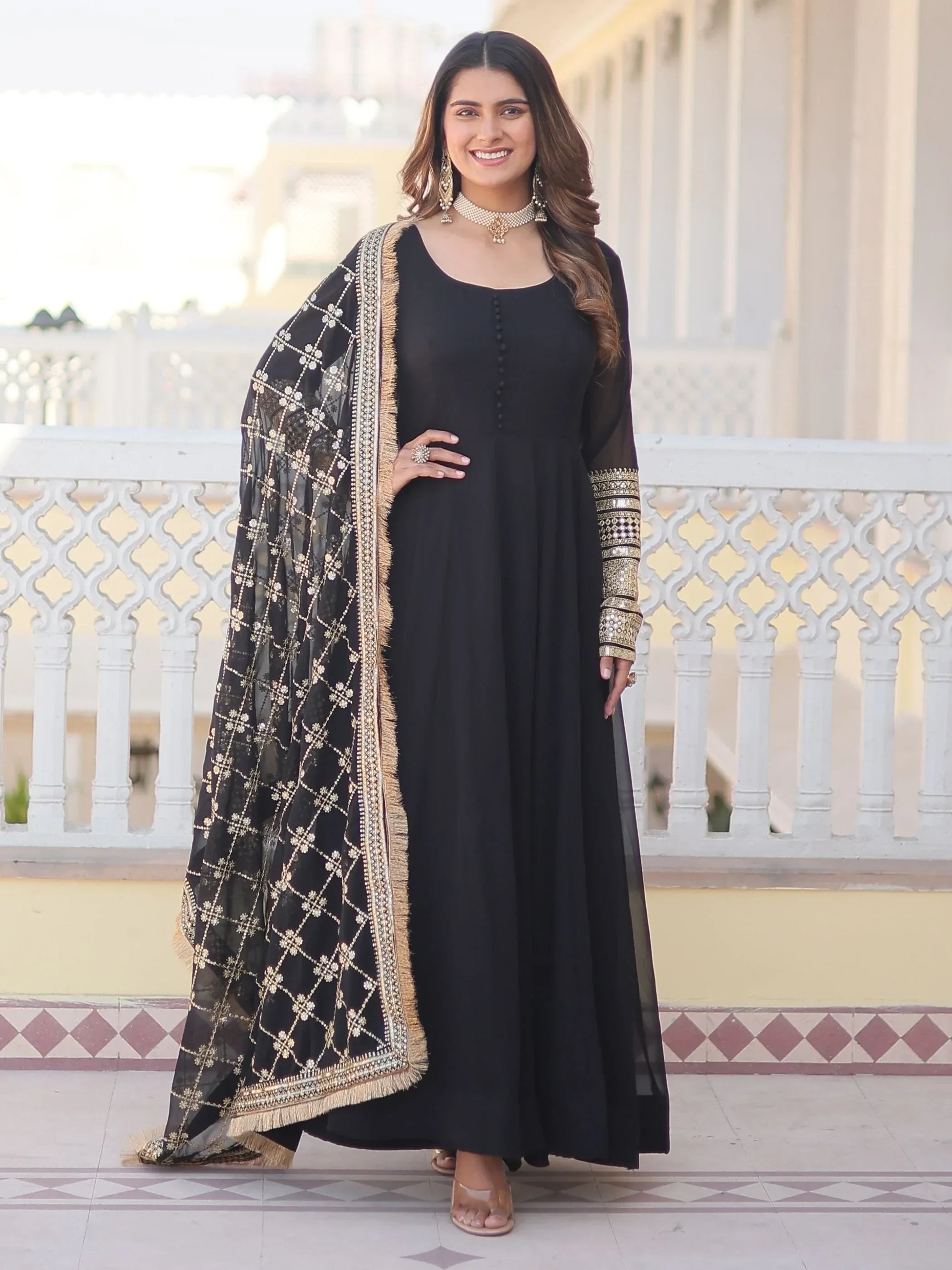 Woman wearing black designer ethnic gown with embroidered dupatta and gold accessories
