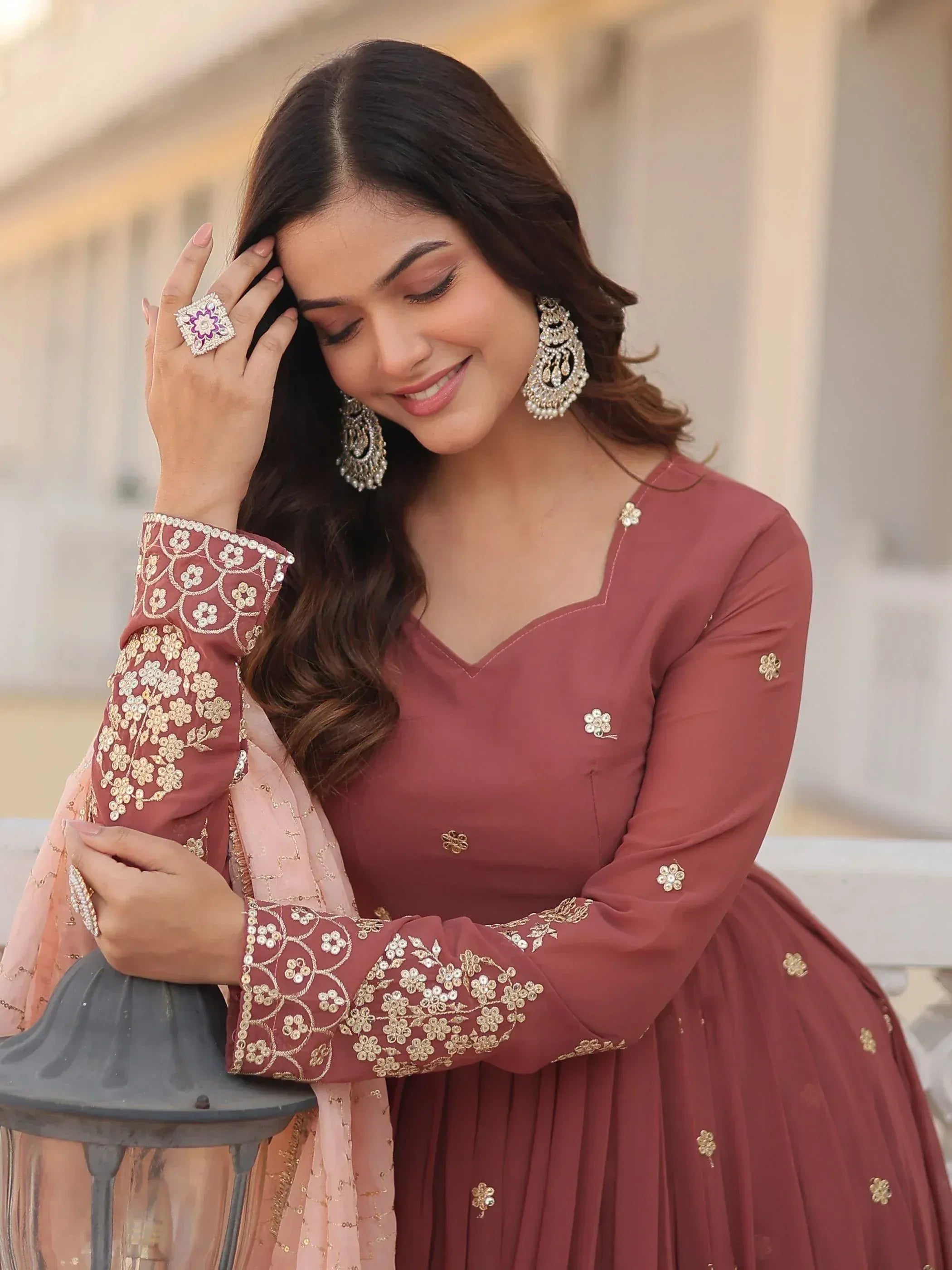 Elegant maroon ethnic gown with gold floral embroidery, paired with statement jewelry for festive occasions