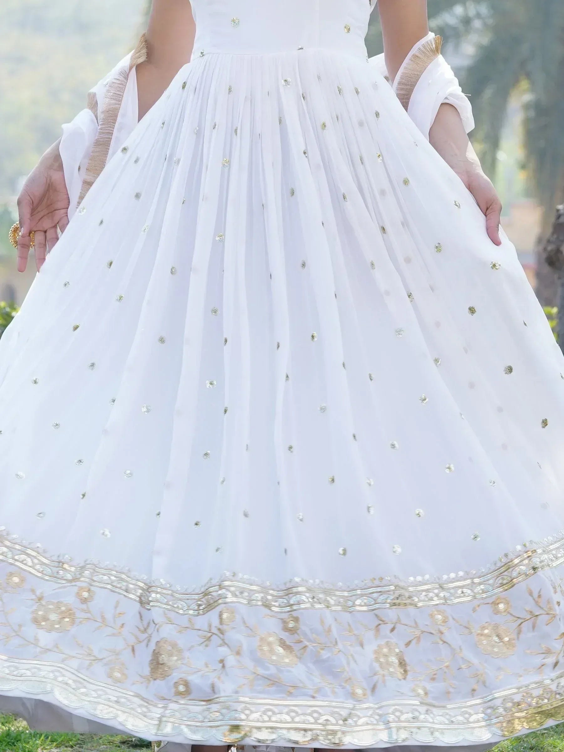 White ethnic gown with gold floral embroidery and sequin detailing, perfect for Indian weddings or festive occasions.