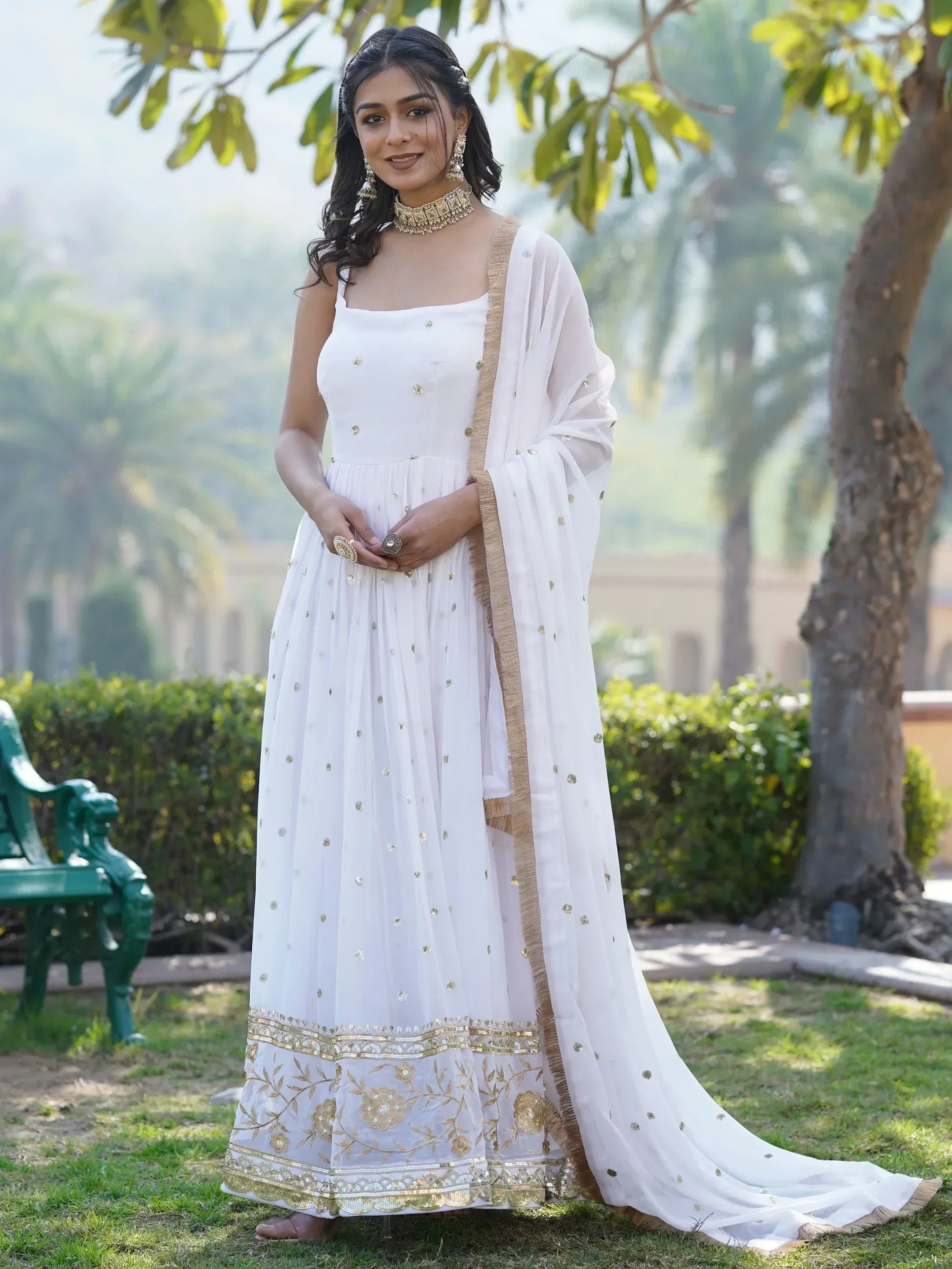 White ethnic gown with gold embroidery and dupatta, perfect for Indian weddings or festive occasions.