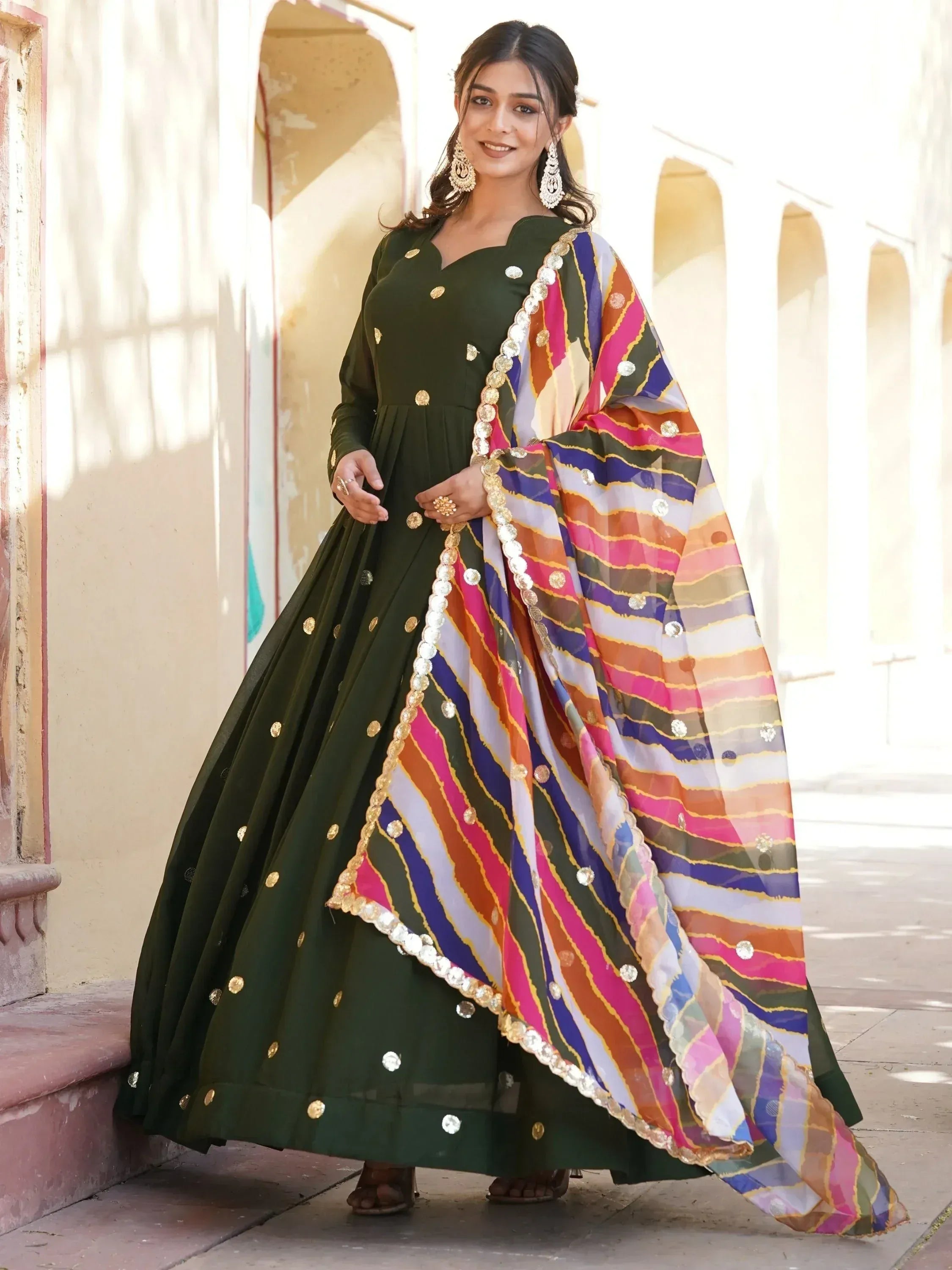 Green ethnic anarkali with gold polka dots and colorful striped dupatta, perfect for Indian festive occasions.