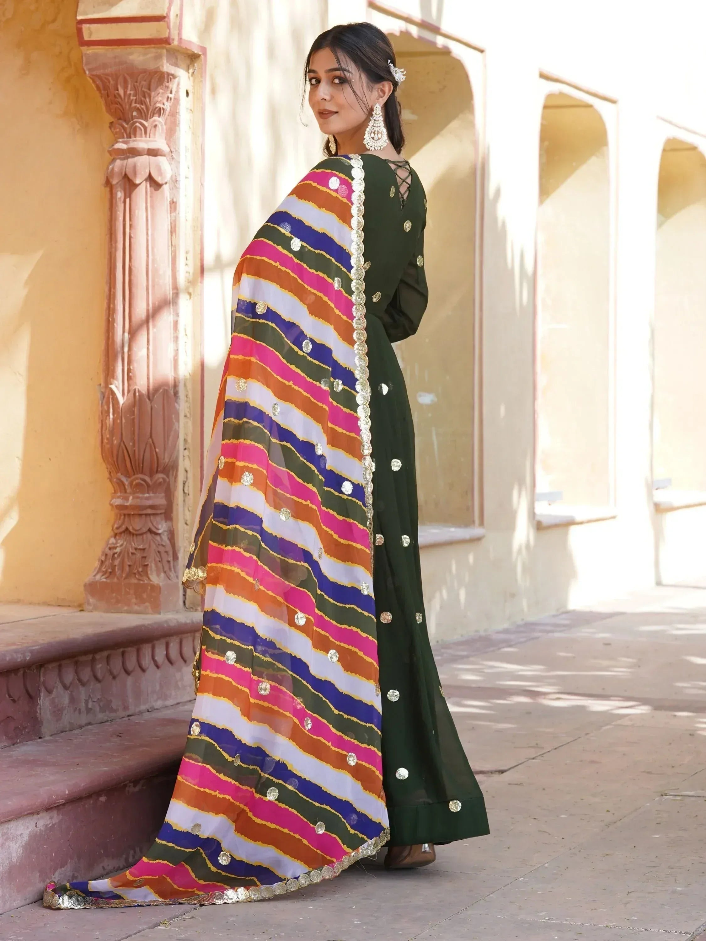 Woman in green ethnic gown with colorful striped dupatta, traditional Indian wear for festive occasions