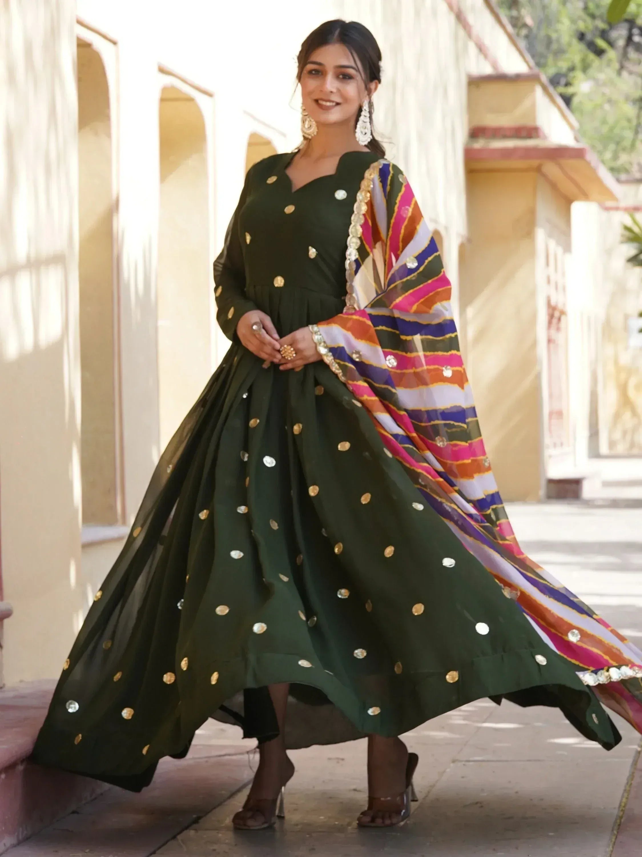 Green ethnic gown with gold embellishments and colorful dupatta, perfect for Indian occasions.