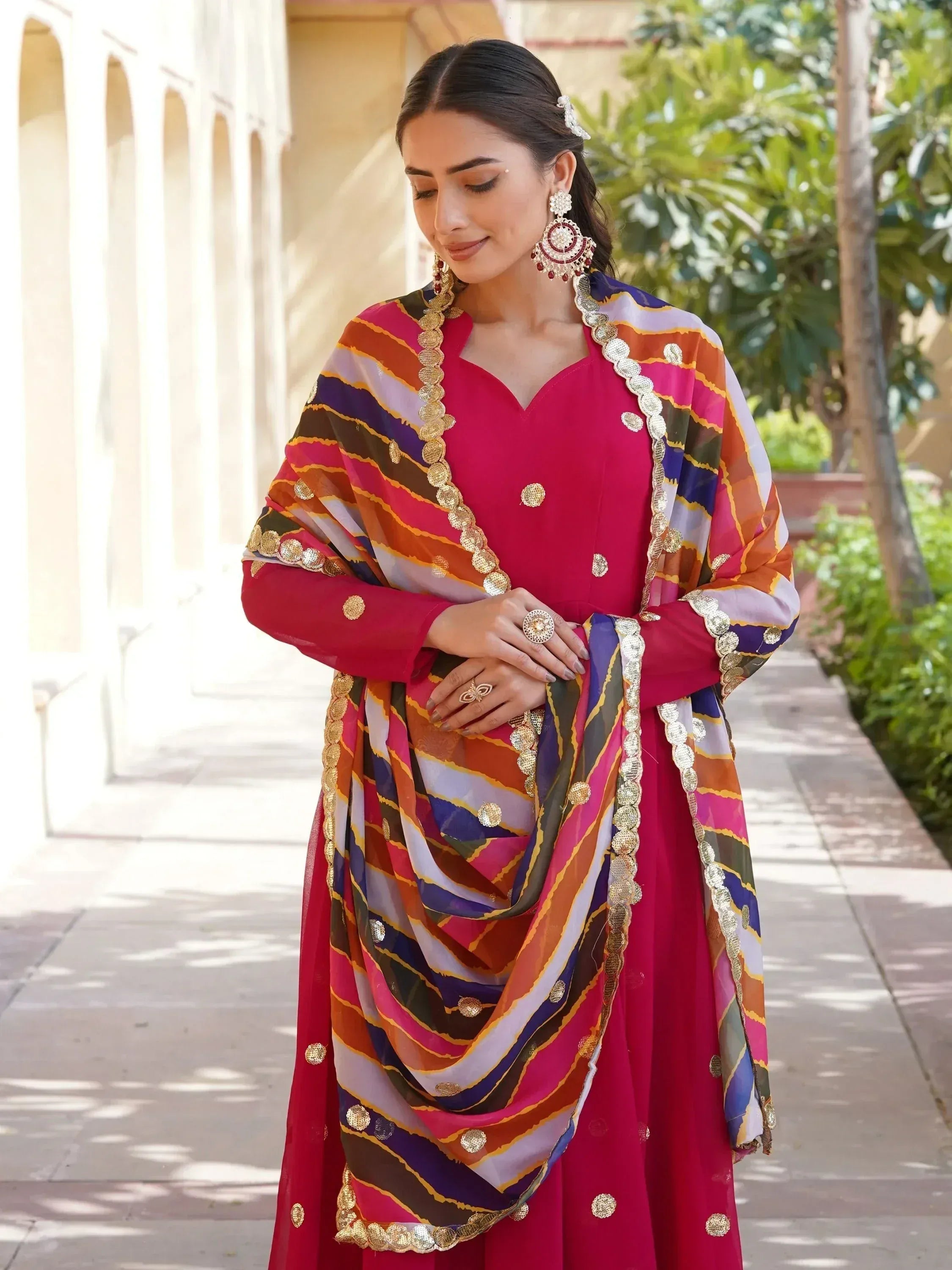 Vibrant pink Indian ethnic salwar kameez with colorful striped dupatta and gold embellishments
