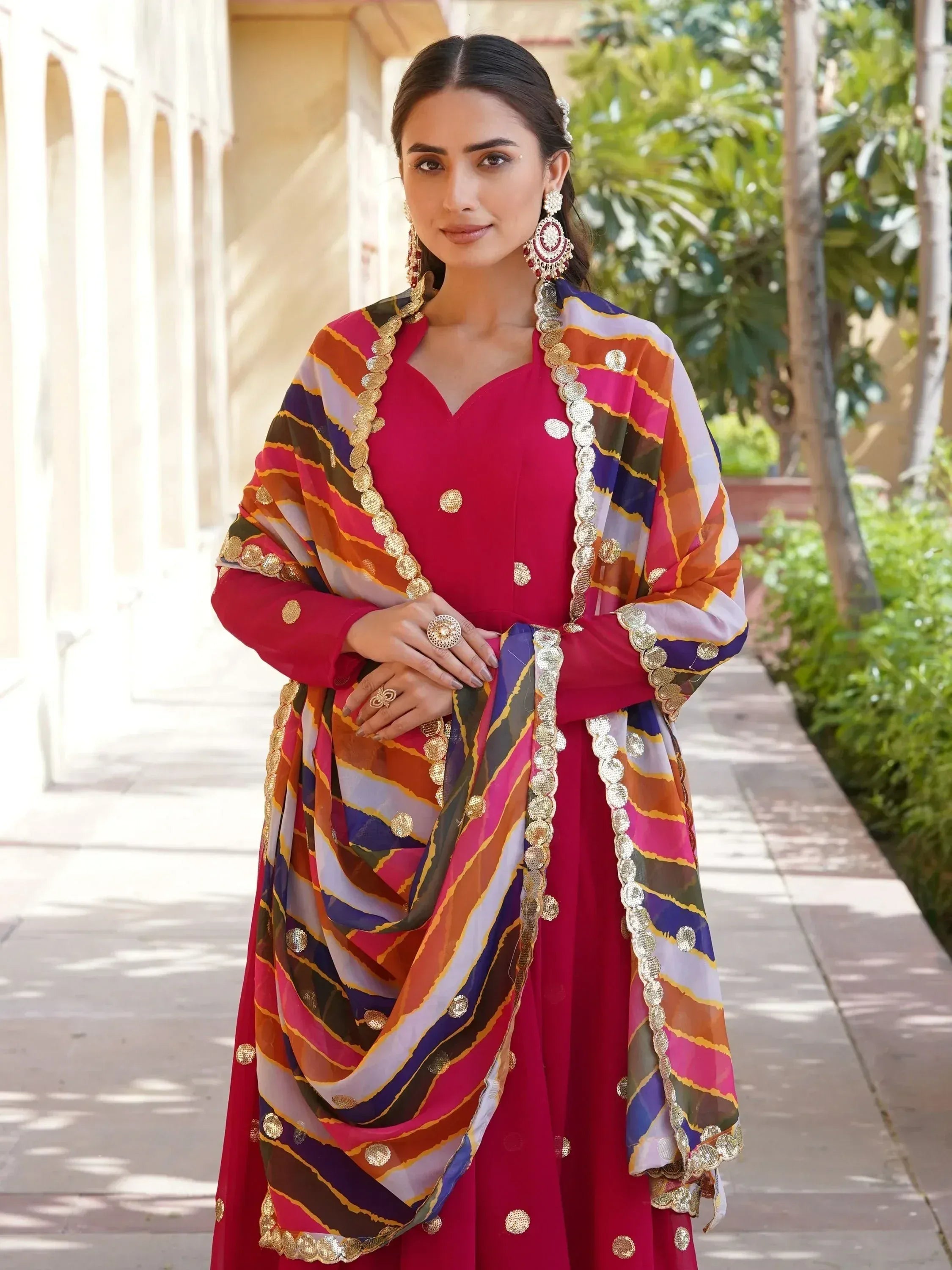 Vibrant red ethnic salwar kameez with colorful striped dupatta and gold embellishments, perfect for festive occasions.