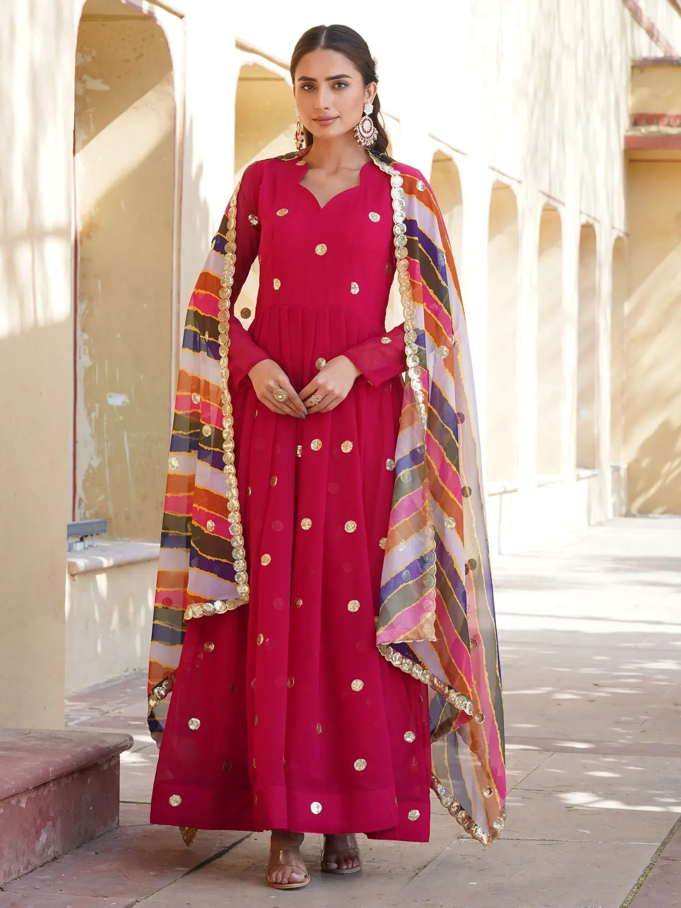 Elegant magenta anarkali with gold embroidery and colorful striped dupatta, perfect for Indian ethnic occasions.