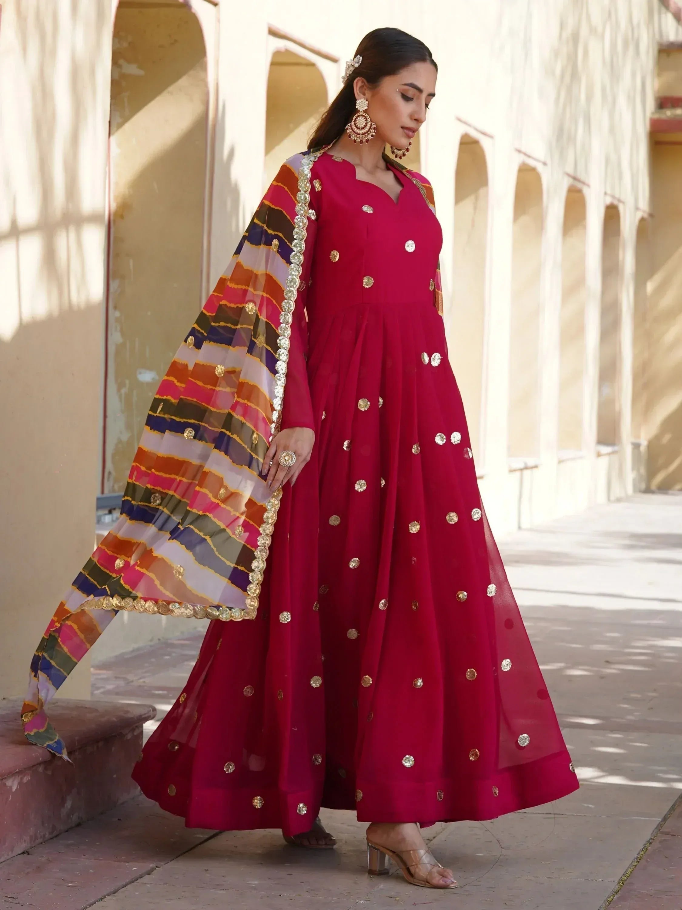 Elegant maroon anarkali with gold mirror work and colorful striped dupatta, perfect for Indian ethnic occasions.