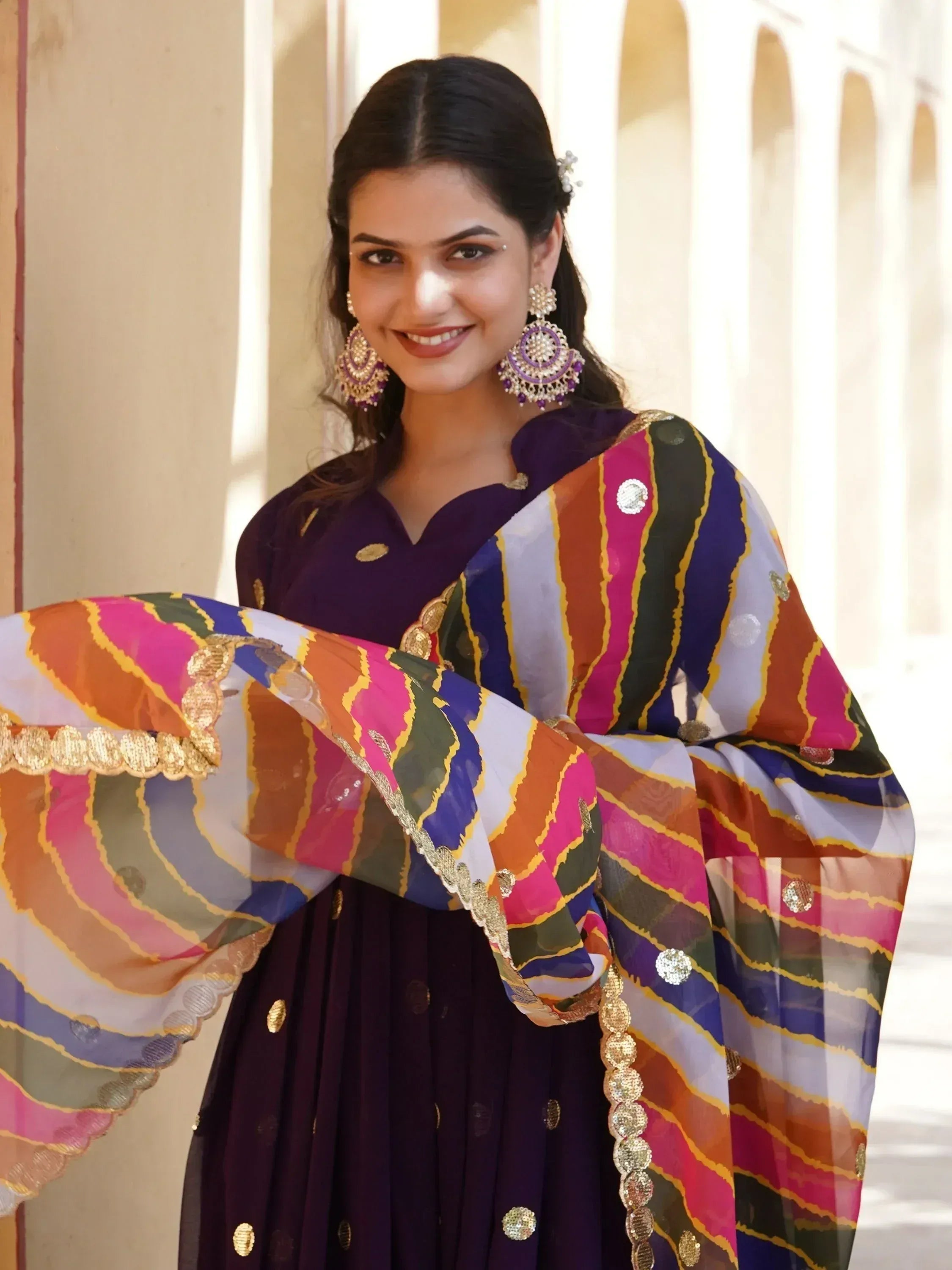 Woman in purple ethnic gown with colorful striped dupatta, perfect for Indian festive occasions