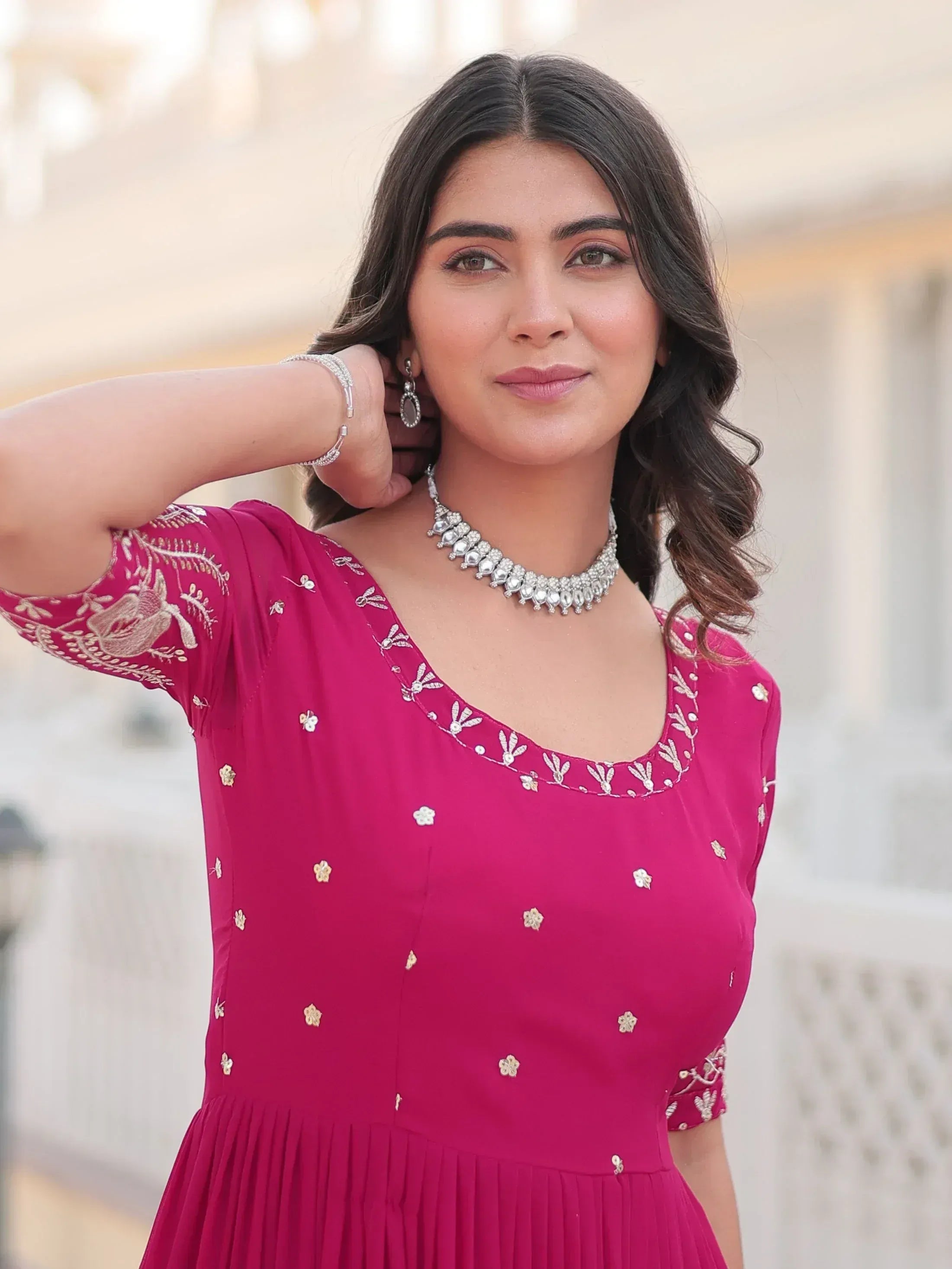 Woman in pink embroidered ethnic gown with gold floral motifs, styled with statement jewelry for festive occasions