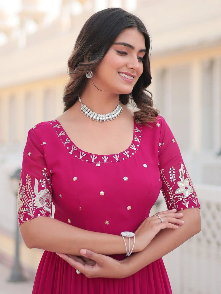Woman in pink embroidered ethnic gown with floral detailing and jewelry, perfect for Indian occasions
