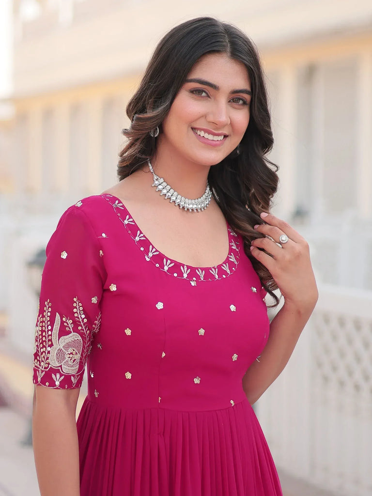 Woman in magenta ethnic gown with gold embroidery, perfect for Indian occasions and festive wear.