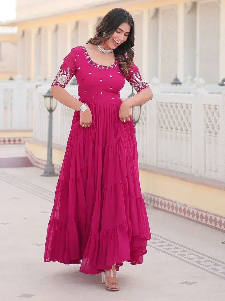 Woman in magenta ethnic gown with embroidery, perfect for Indian occasions and festive wear.